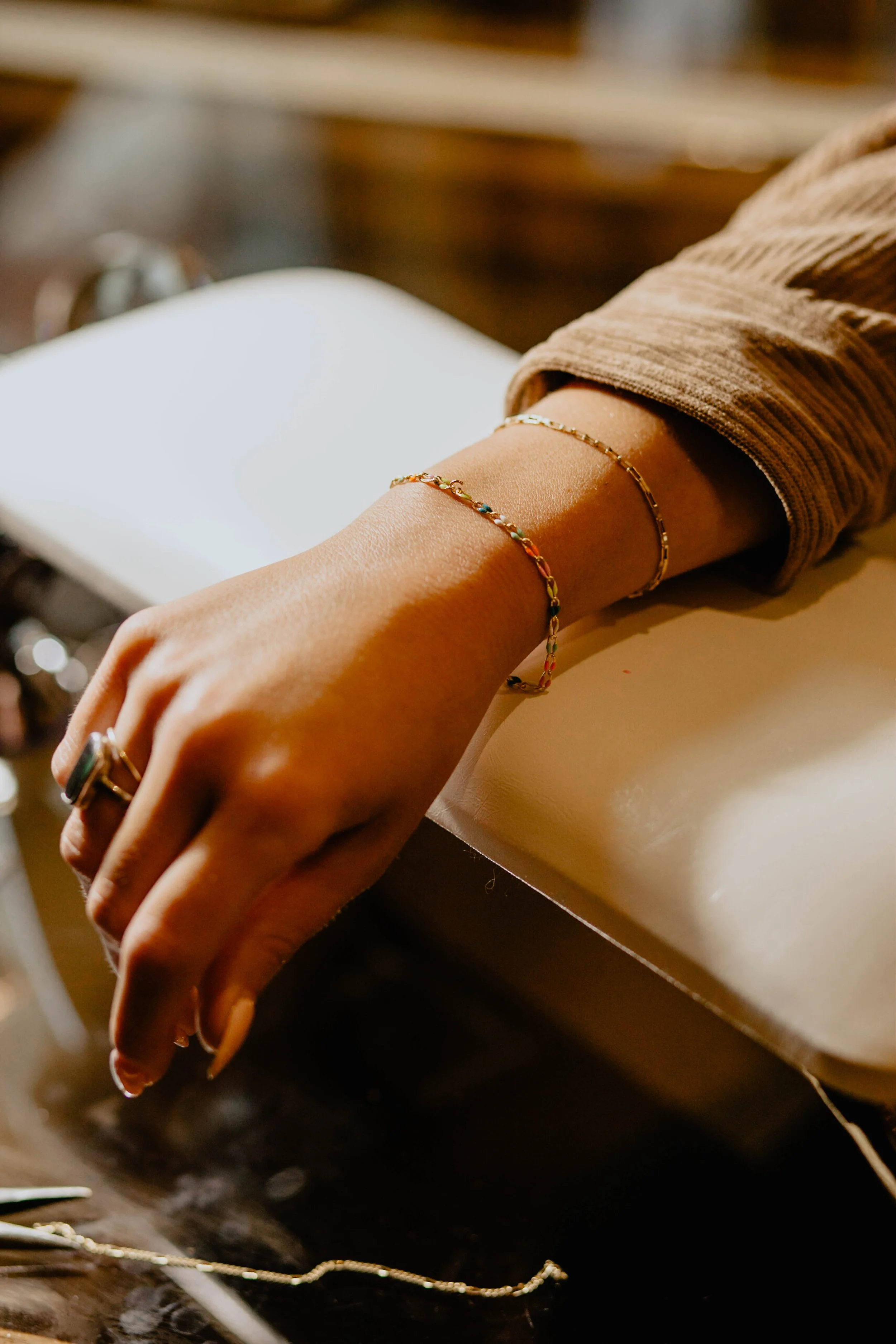 A person’s hand and wrist resting on a surface, wearing jewelry including rings and bracelets, with a blurred background. Seattle professional head shot photography