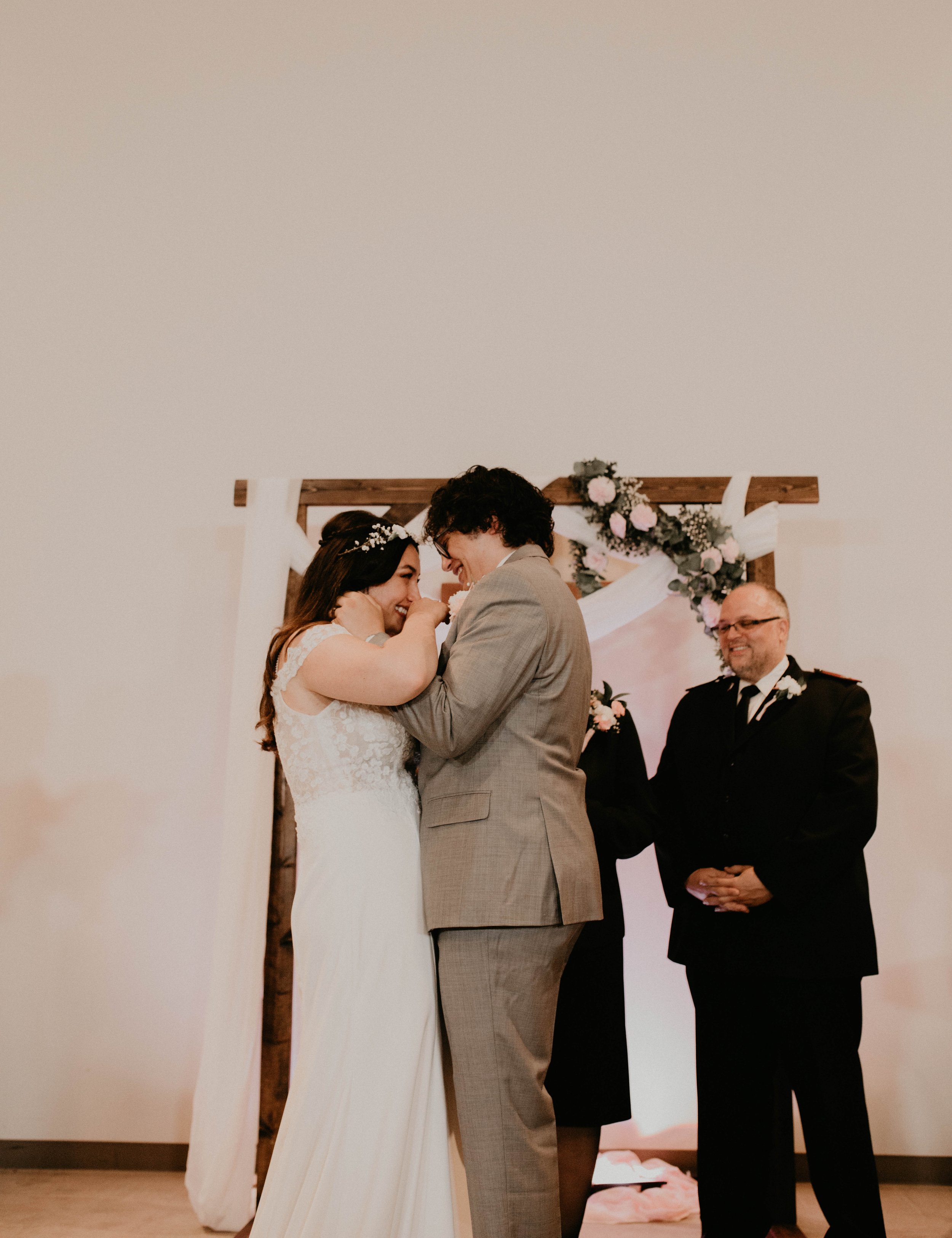 A bride and groom sharing a moment during their wedding ceremony, with an officiant standing beside them Seattle, WA wedding photography.
