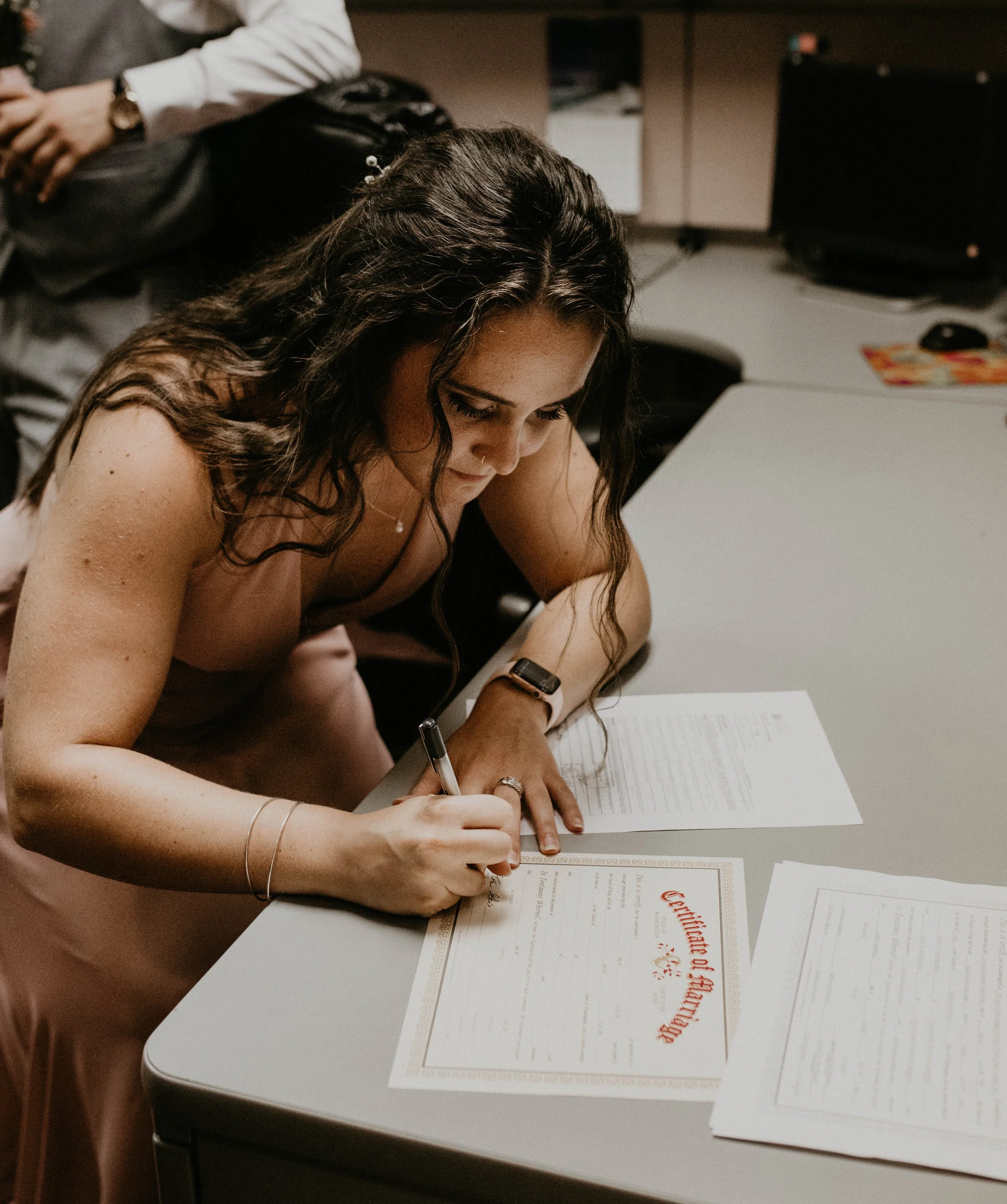 Woman signing a certificate of authenticity at a desk, with paperwork and a pen. Seattle, WA wedding photography.