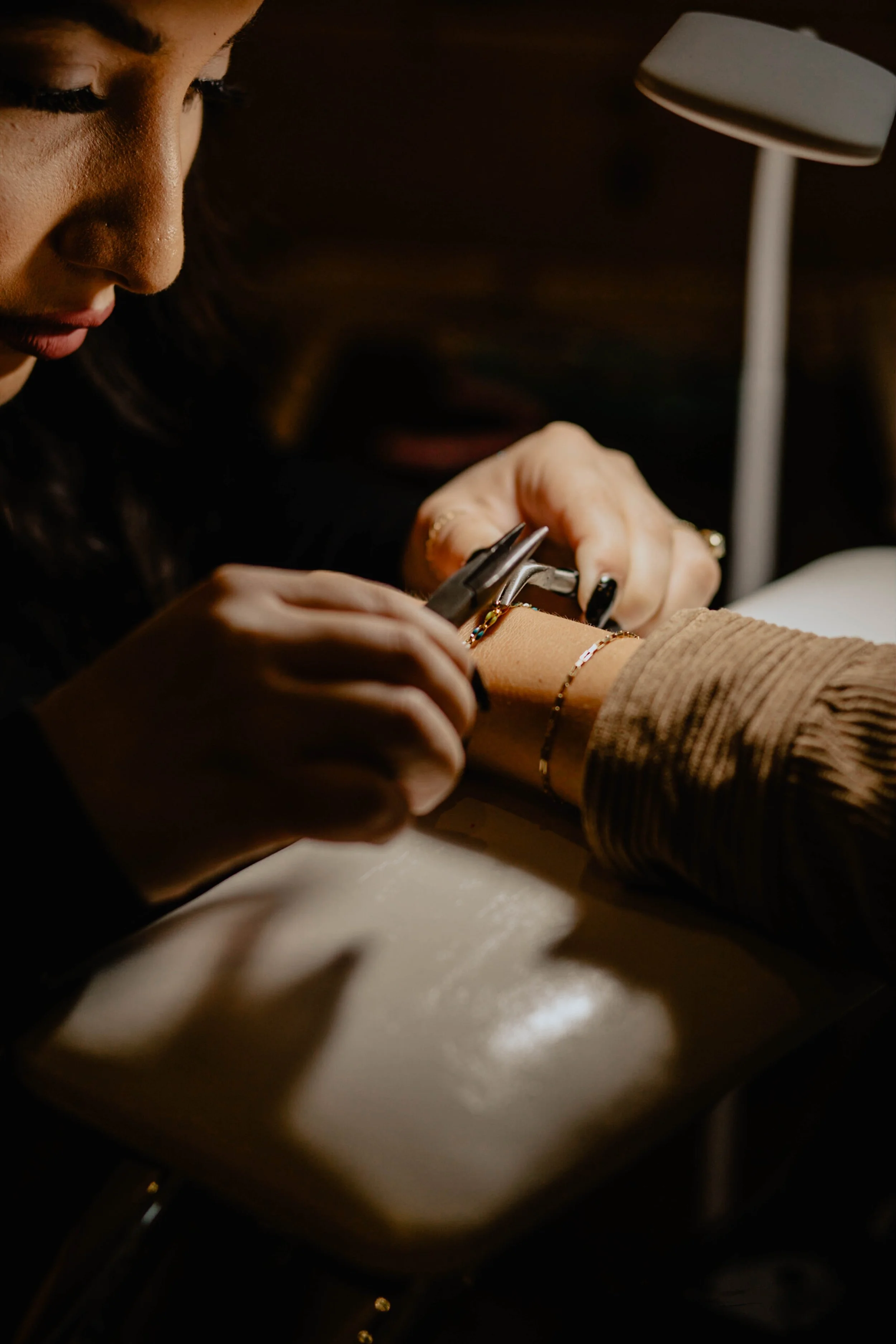 A woman is giving a manicure to a person's hand, with a small lamp providing focused light. Seattle professional head shot photography