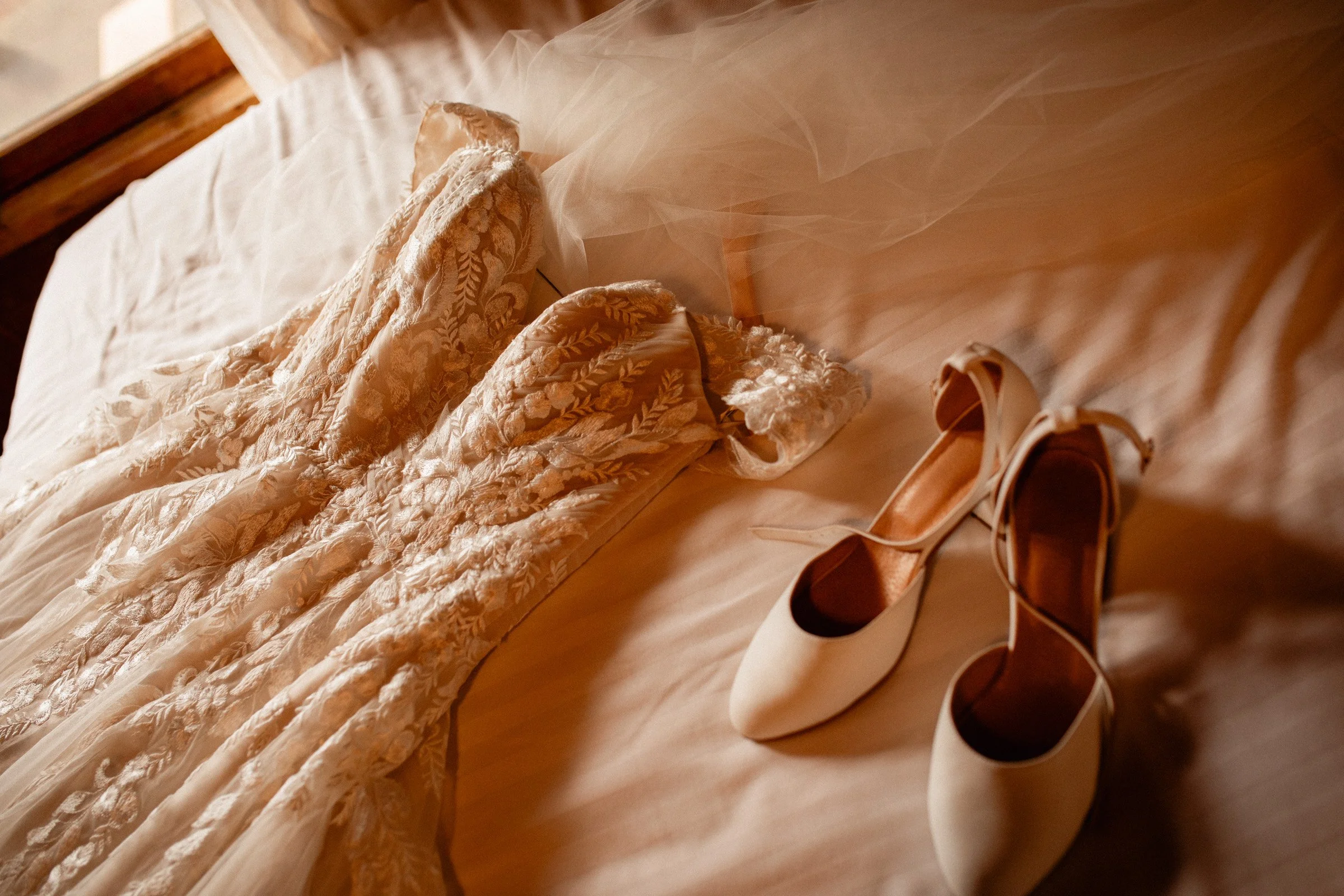 Wedding dress and bridal shoes on the bed in the Lake Crescent Lodge bridal suite before a Lake Crescent wedding in Port Angeles, WA.