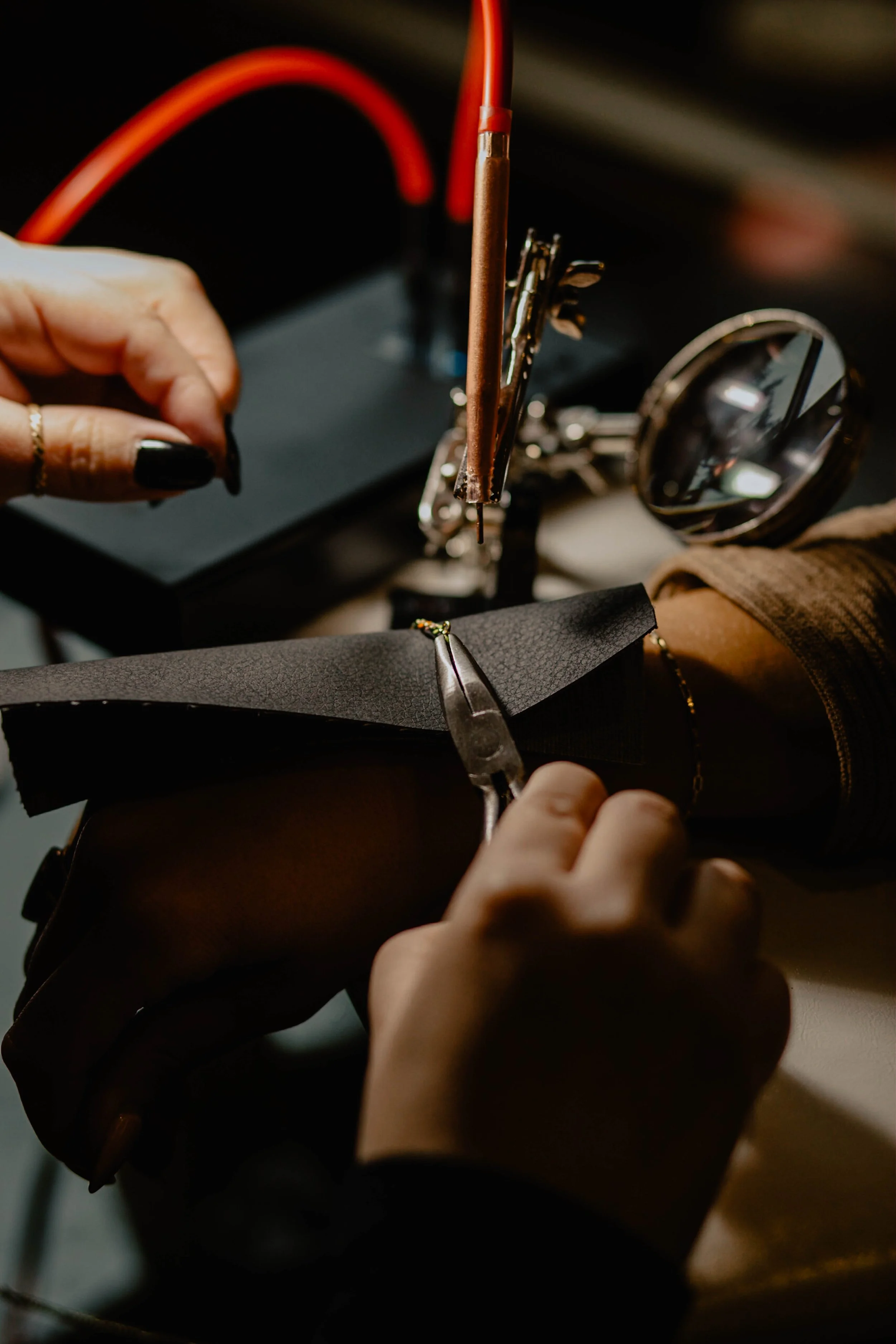 Hands working on a shoe, using tools like pliers and a screwdriver, in a workshop with a magnifying glass nearby. Seattle professional head shot photography