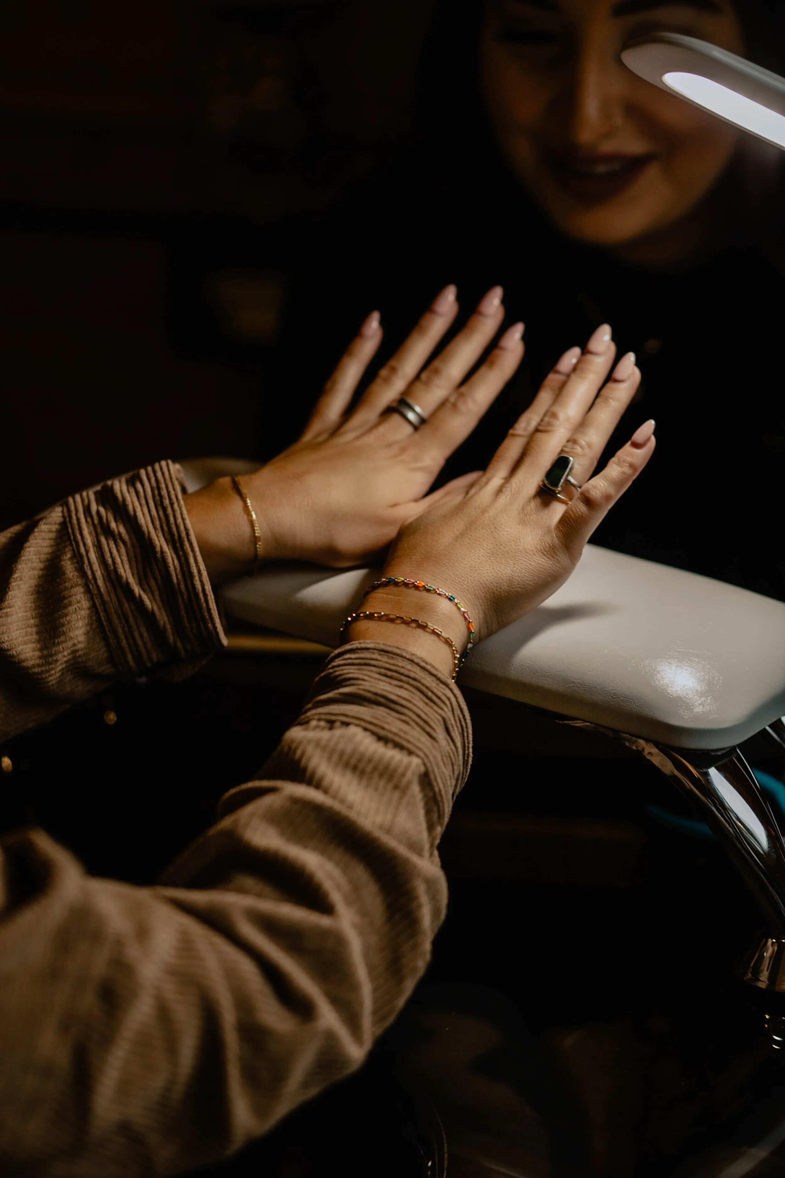 A person getting a manicure at a salon, with hands resting on a padded surface and a manicurist applying nail polish. Seattle professional head shot photography