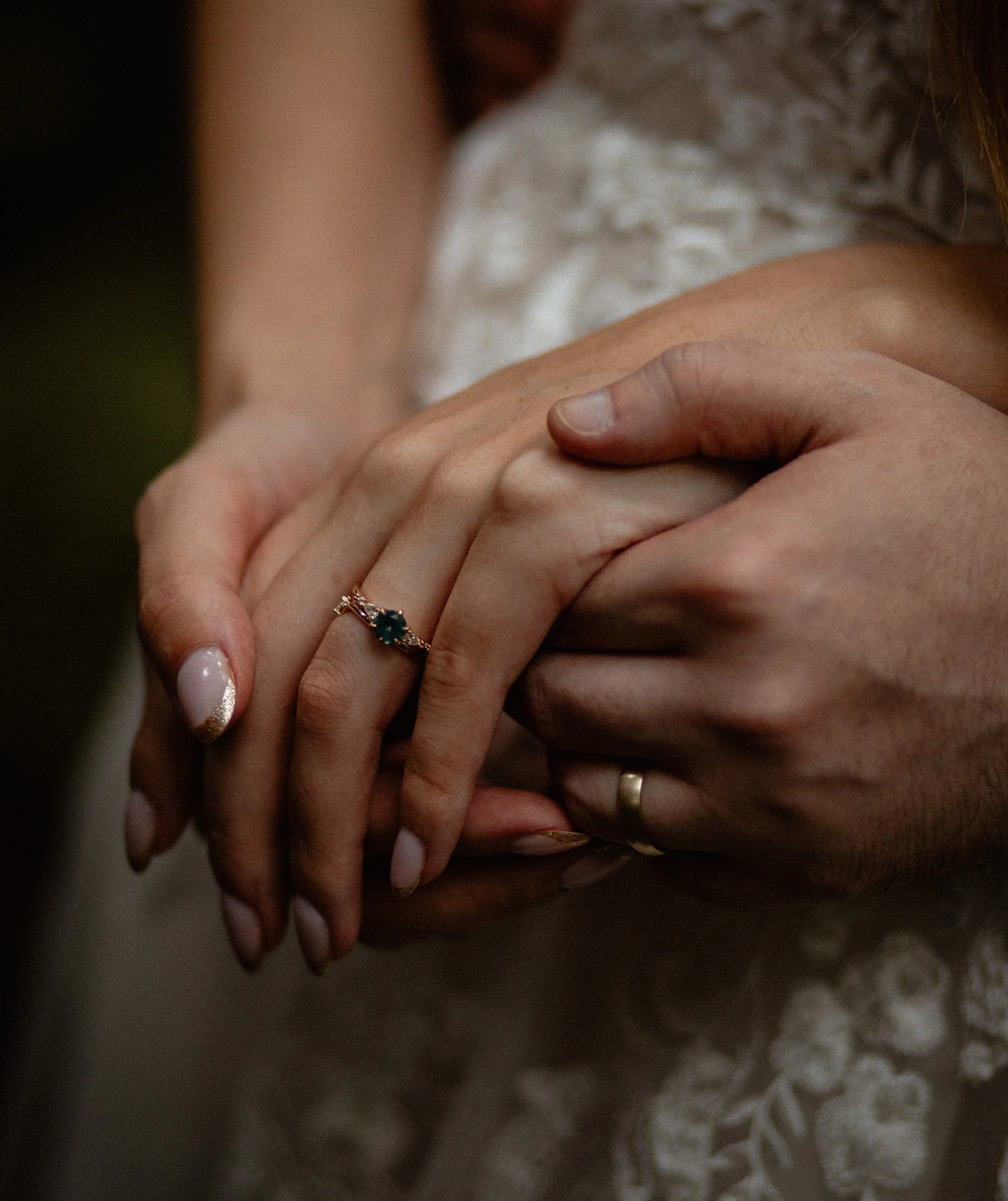 Close-up of the bride and groom’s hands intertwined, featuring the bride’s emerald diamond ring during their Lake Crescent Lodge wedding in Port Angeles, WA.