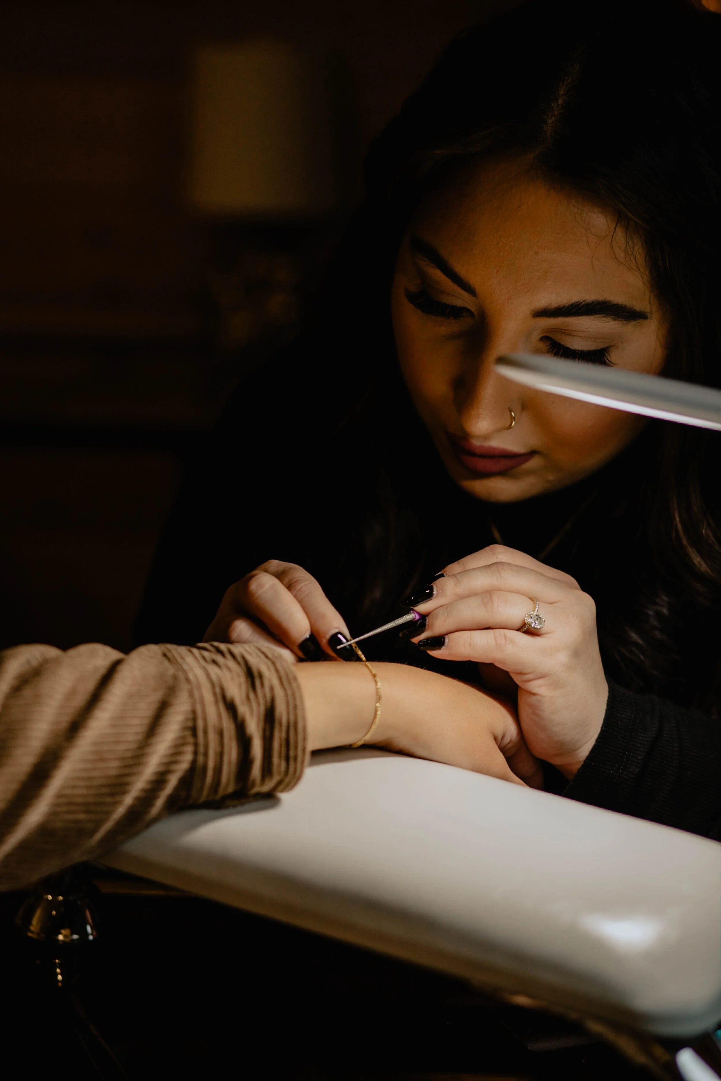 A woman getting a tattoo on her wrist from a tattoo artist in a dimly lit room. Seattle professional head shot photography