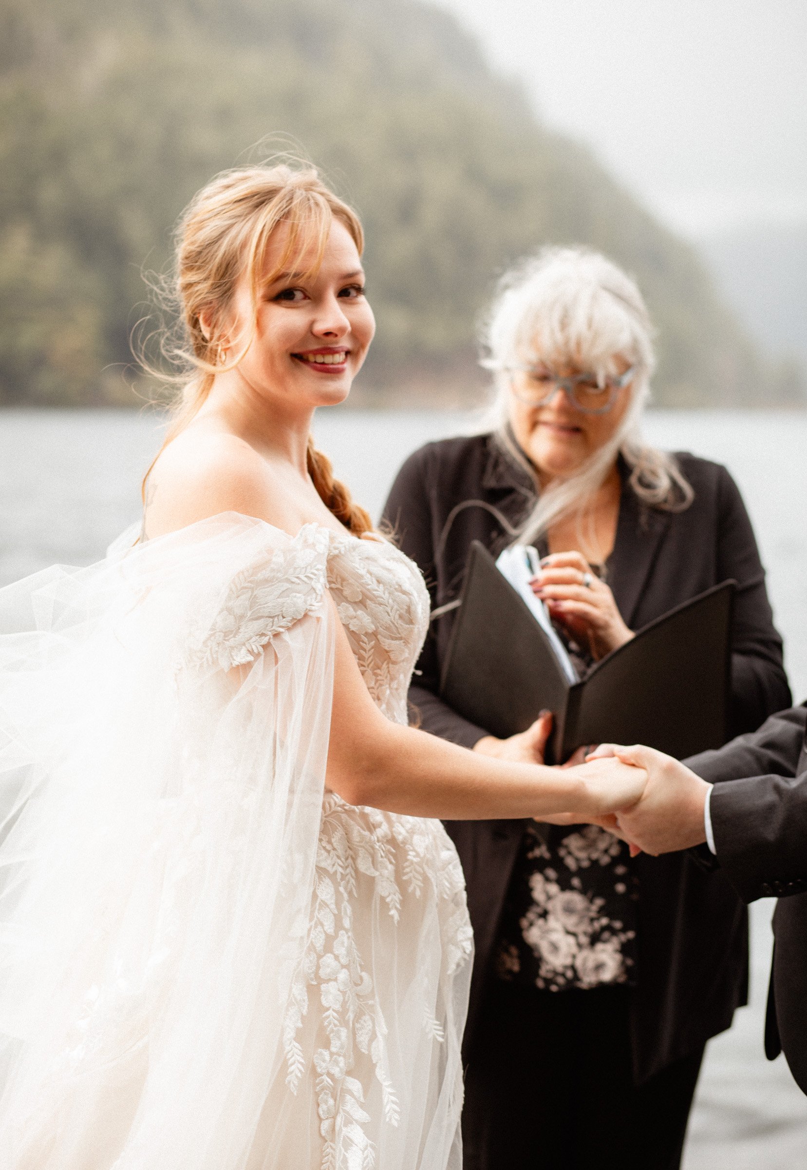 Bride at the altar flashing a bright smile toward the camera during her Lake Crescent Lodge wedding ceremony in Port Angeles, WA.