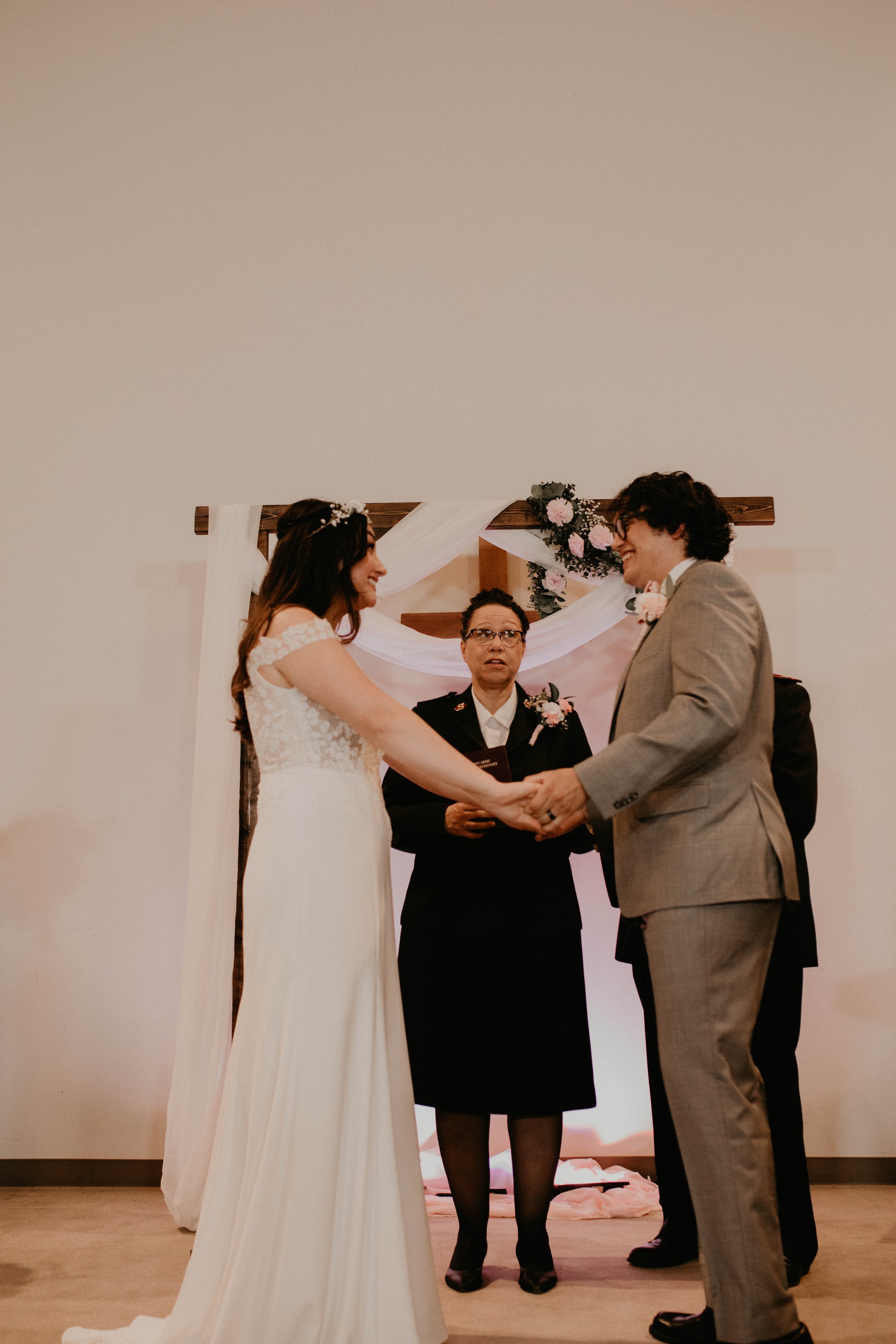 A couple getting married, holding hands and smiling at each other during their wedding ceremony, with an officiant standing behind them. Seattle, WA wedding photography.