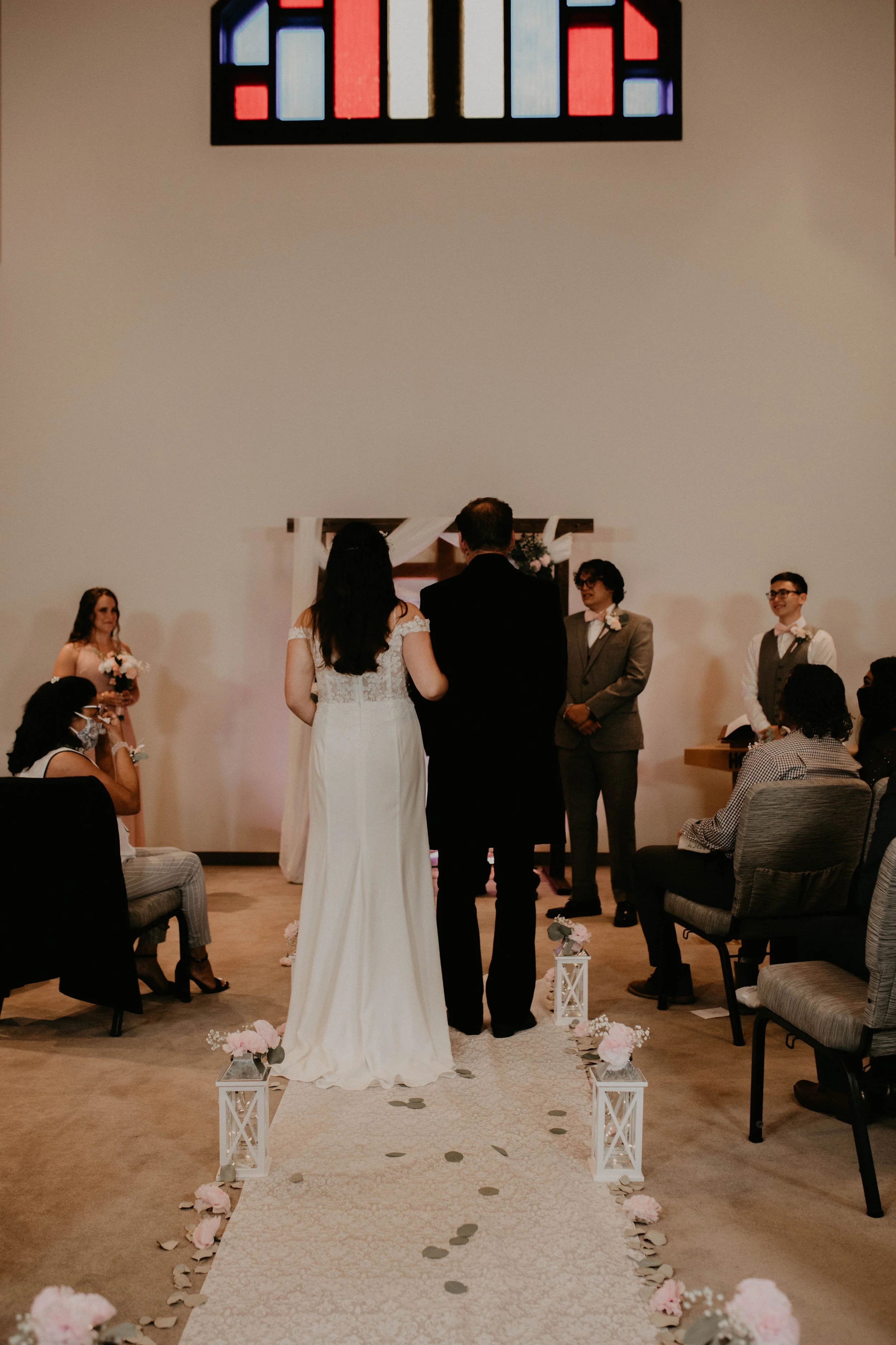 Bride and groom standing together during a wedding ceremony, facing a small altar with officiant and witnesses, in a decorated indoor venue. Seattle, WA wedding photography.