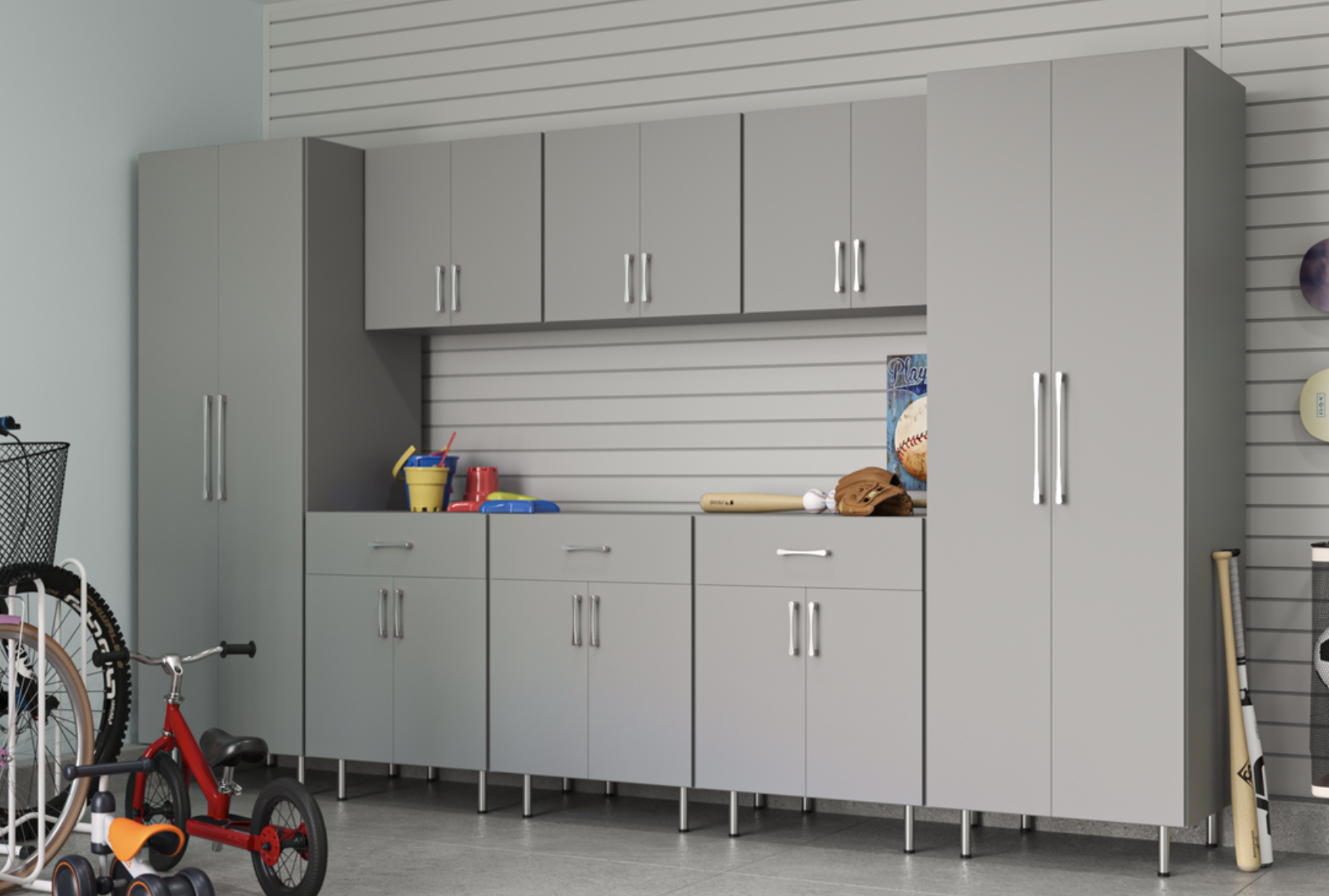 Gray storage cabinets in a garage with sports equipment, including a baseball bat, baseball, glove, helmet, and child's bicycle.