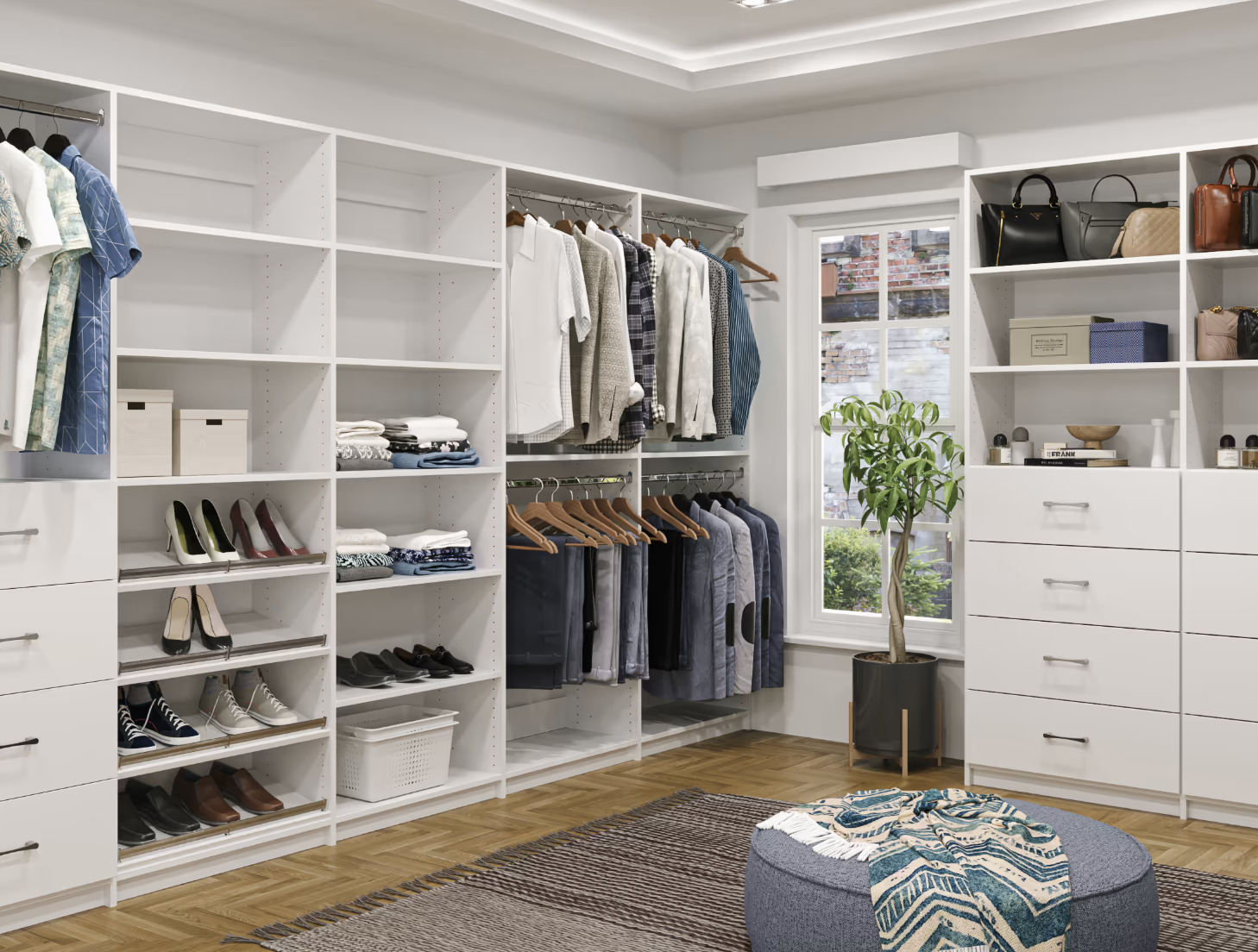 Organized walk-in closet with white shelves filled with clothes, shoes, handbags, and decorative items. There is a potted plant near a window, and a round ottoman with a patterned cloth on top on a rug.