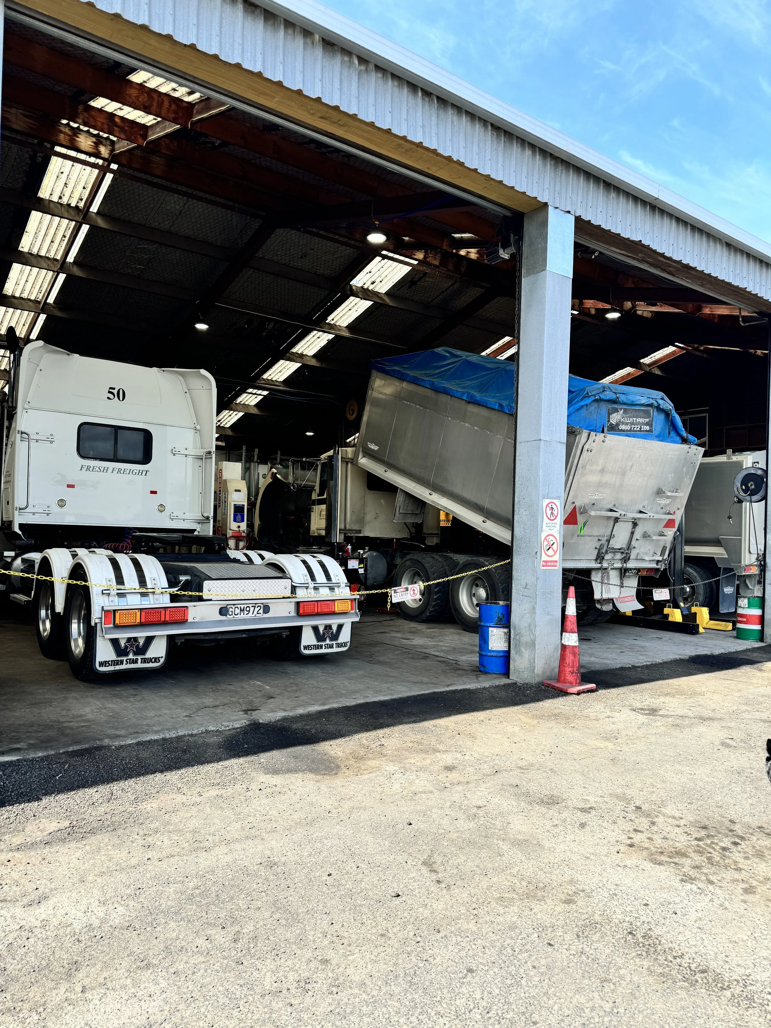 Trucks parked inside workshop being worked on.