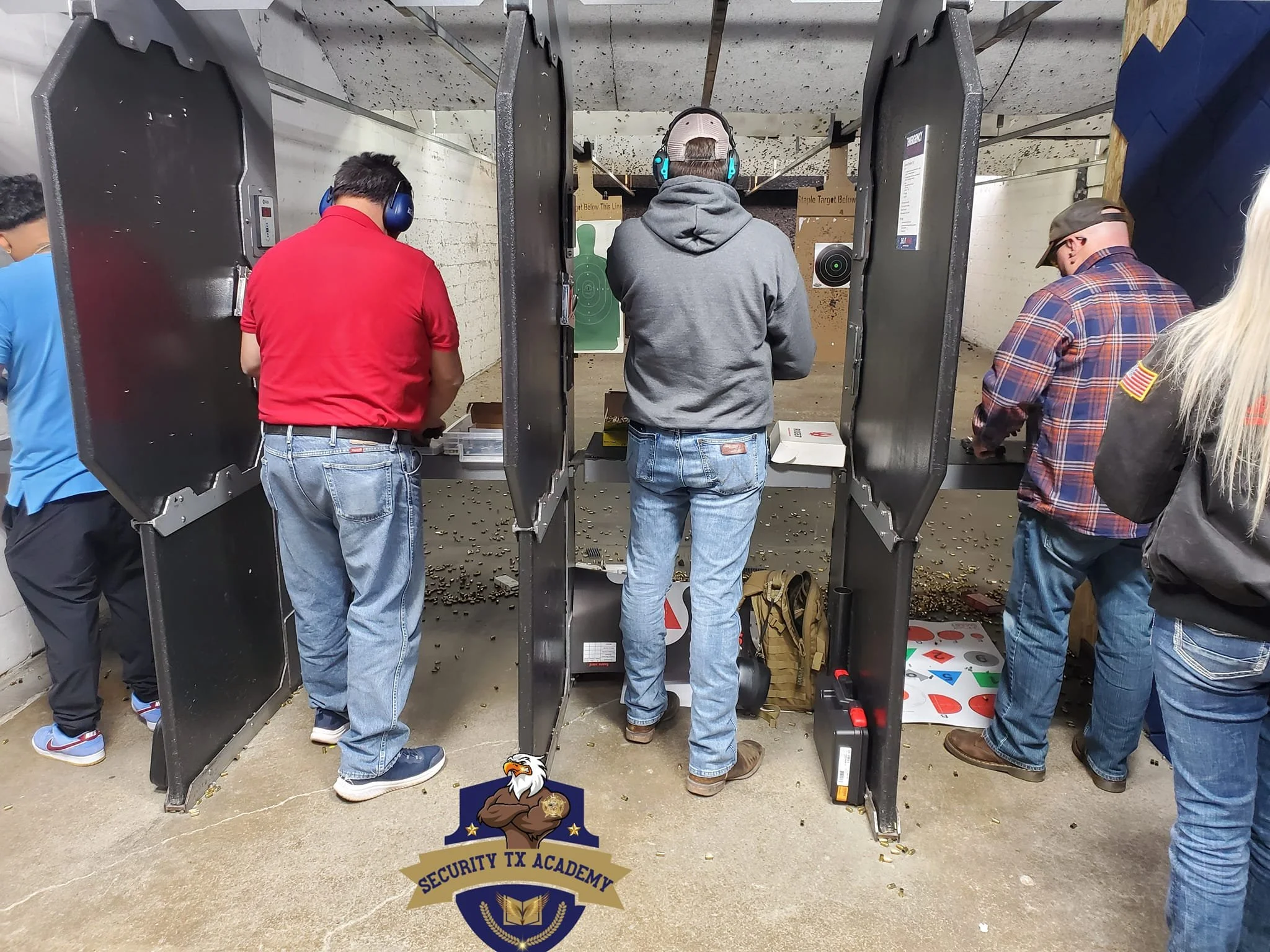 People participating in a shooting practice at an indoor shooting range with protective hearing gear.