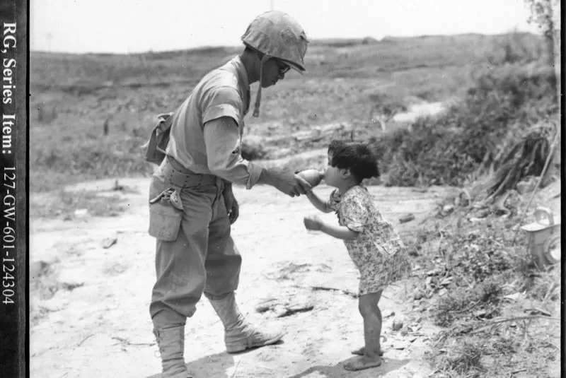 Solider giving water to a child