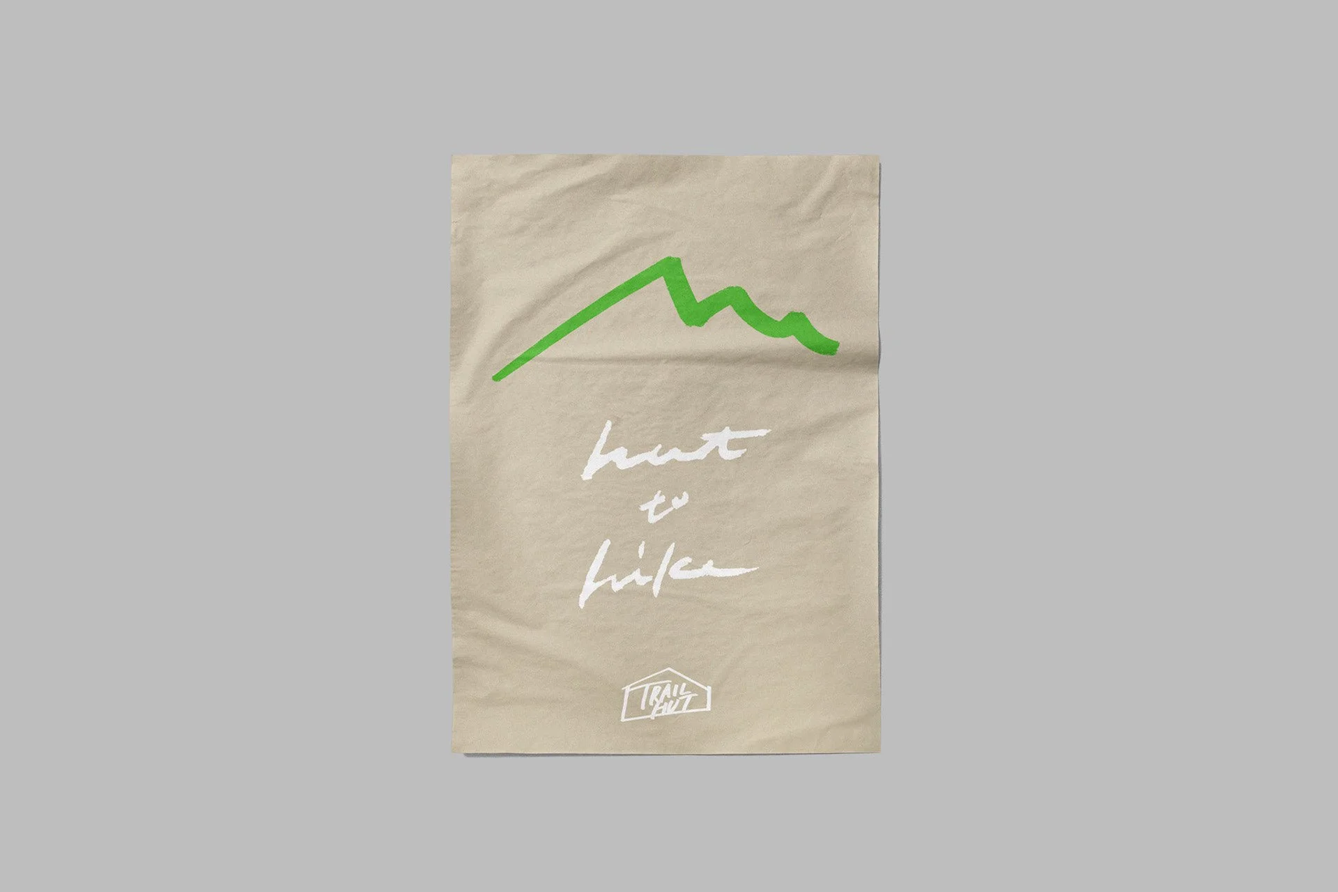 ベージュの紙面に緑の山のラインと「hut to hike」の手書き文字を配置したポスター。下部にロゴを添え、シンプルながらもブランドの思想を伝えるデザイン。Poster design for TRAIL HUT featuring a green mountain line drawing and handwritten text “hut to hike” on beige paper. The logo at the bottom anchors the visual, conveying