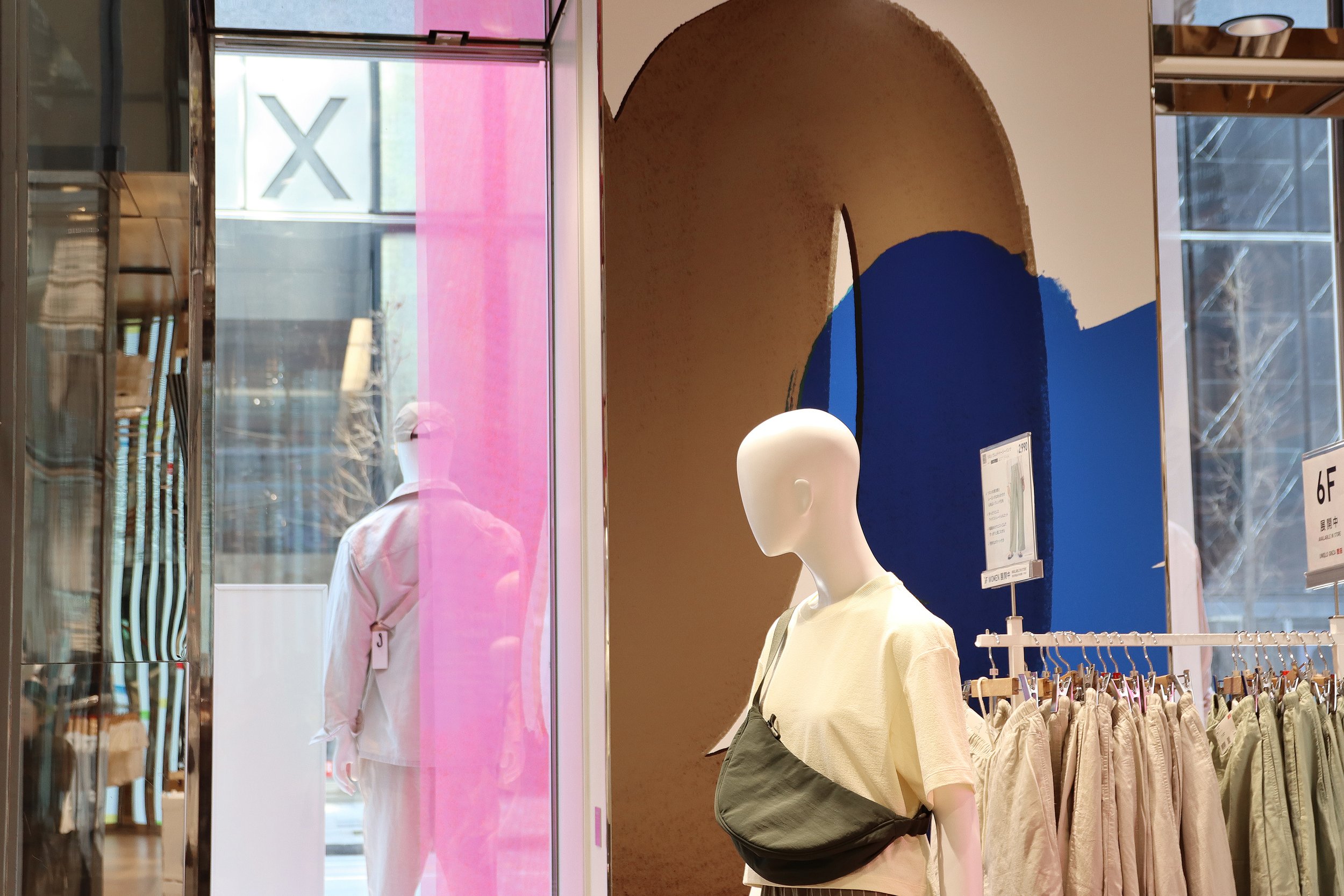 ユニクロ銀座店内、2025年春夏キャンペーンの一環として展示されたブラウンとブルーの抽象アートとマネキン。Inside UNIQLO Ginza: mannequins displayed alongside brown and blue abstract brushstroke art for the 2025 S/S visual campaign by Asami Sato.
