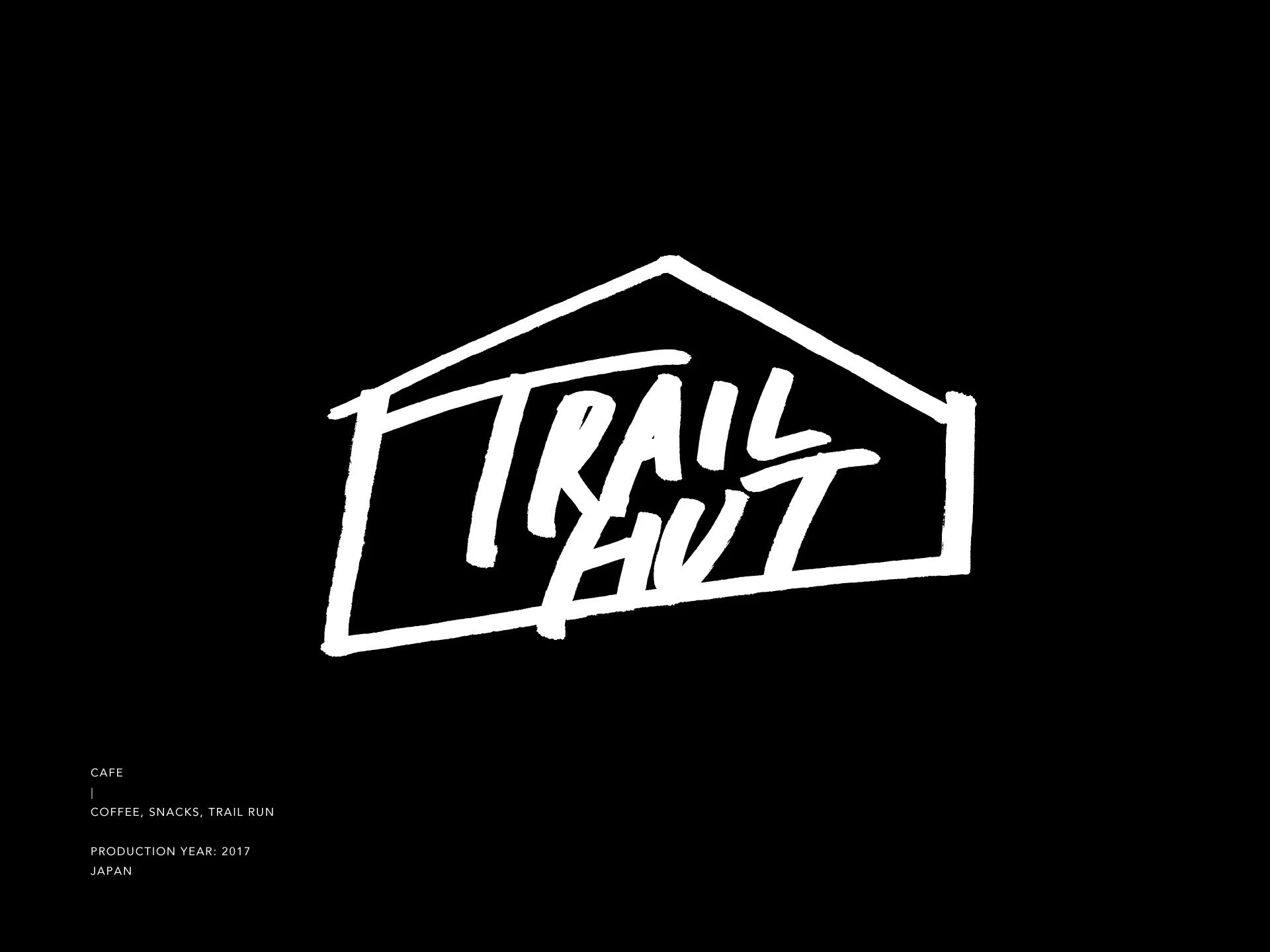黒地に白で描かれたTRAIL HUTのロゴ。小屋のシルエットをモチーフに、力強い手描き文字を収めたビジュアルアイデンティティの中心。The TRAIL HUT logo in white on a black background. A bold hand-drawn typography enclosed within a hut silhouette, serving as the core of the visual identity.