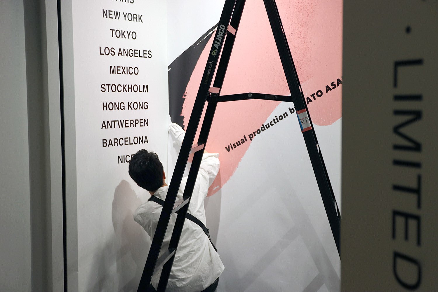 アートイベントのため、筆跡アートが壁面に設営されている様子。Installation view of large-scale brushstroke artwork being applied on a wall for an art event.