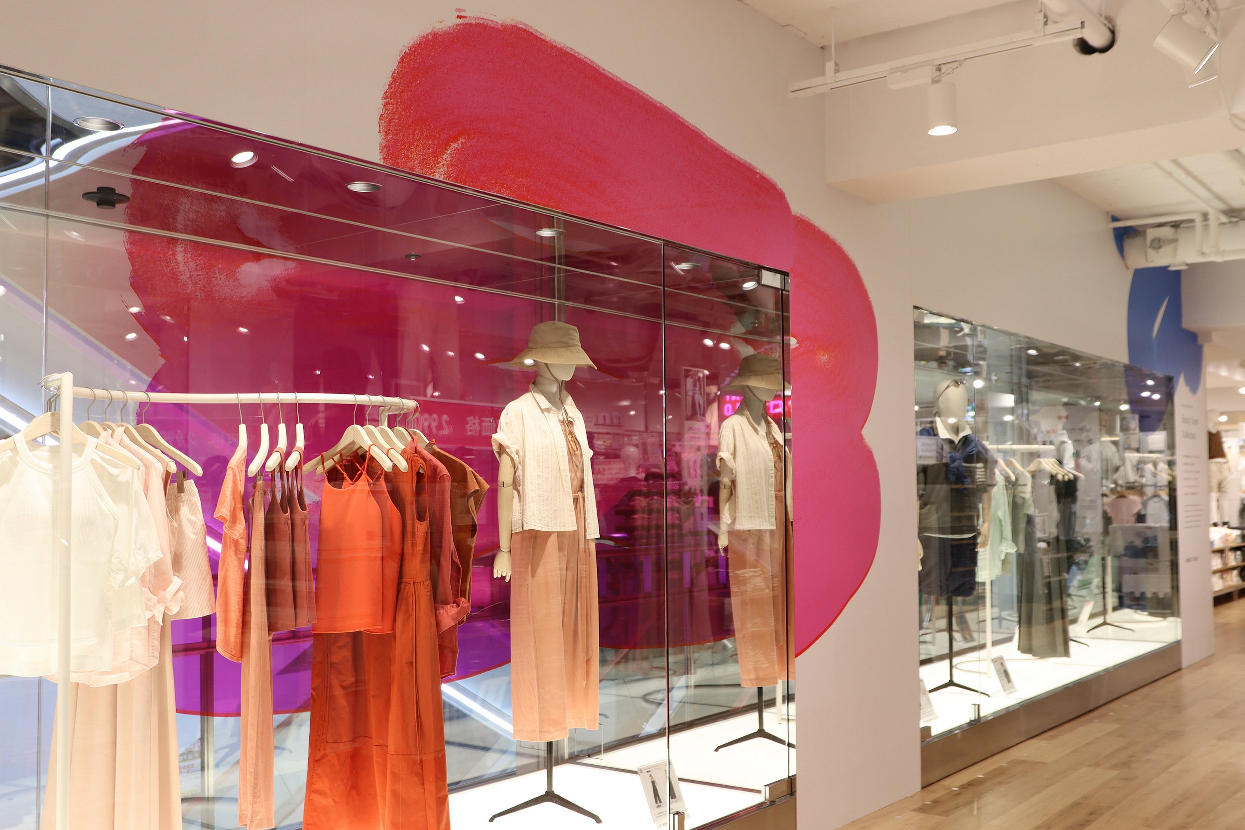 店内のピンクのアートウォールとリネン素材のウィメンズ商品が並ぶユニクロの春夏ディスプレイ(アートワーク:サトウアサミ)Interior pink art wall display with women’s linen apparel at UNIQLO for the 2025 Spring/Summer collection (Artwork by Asami Sato)