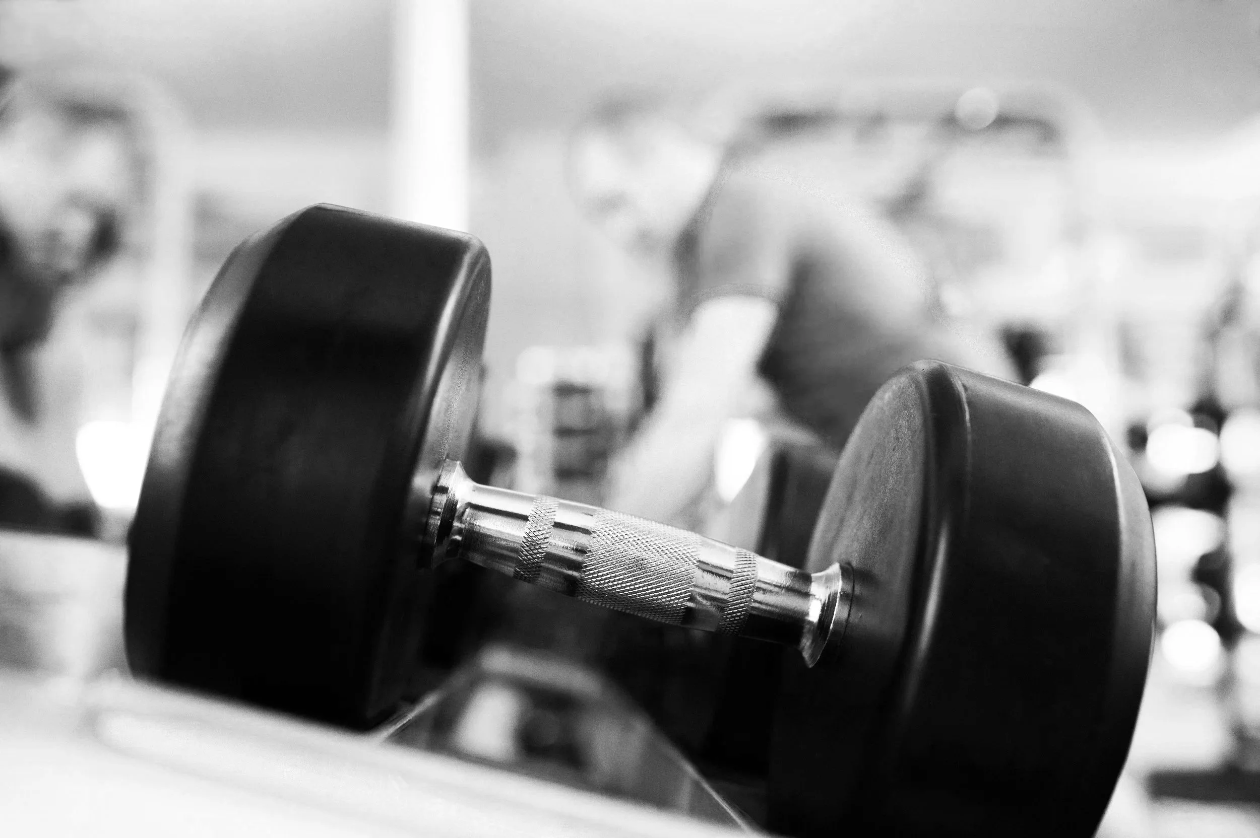 Close-up of a dumbbell in a gym with blurry background of people working out