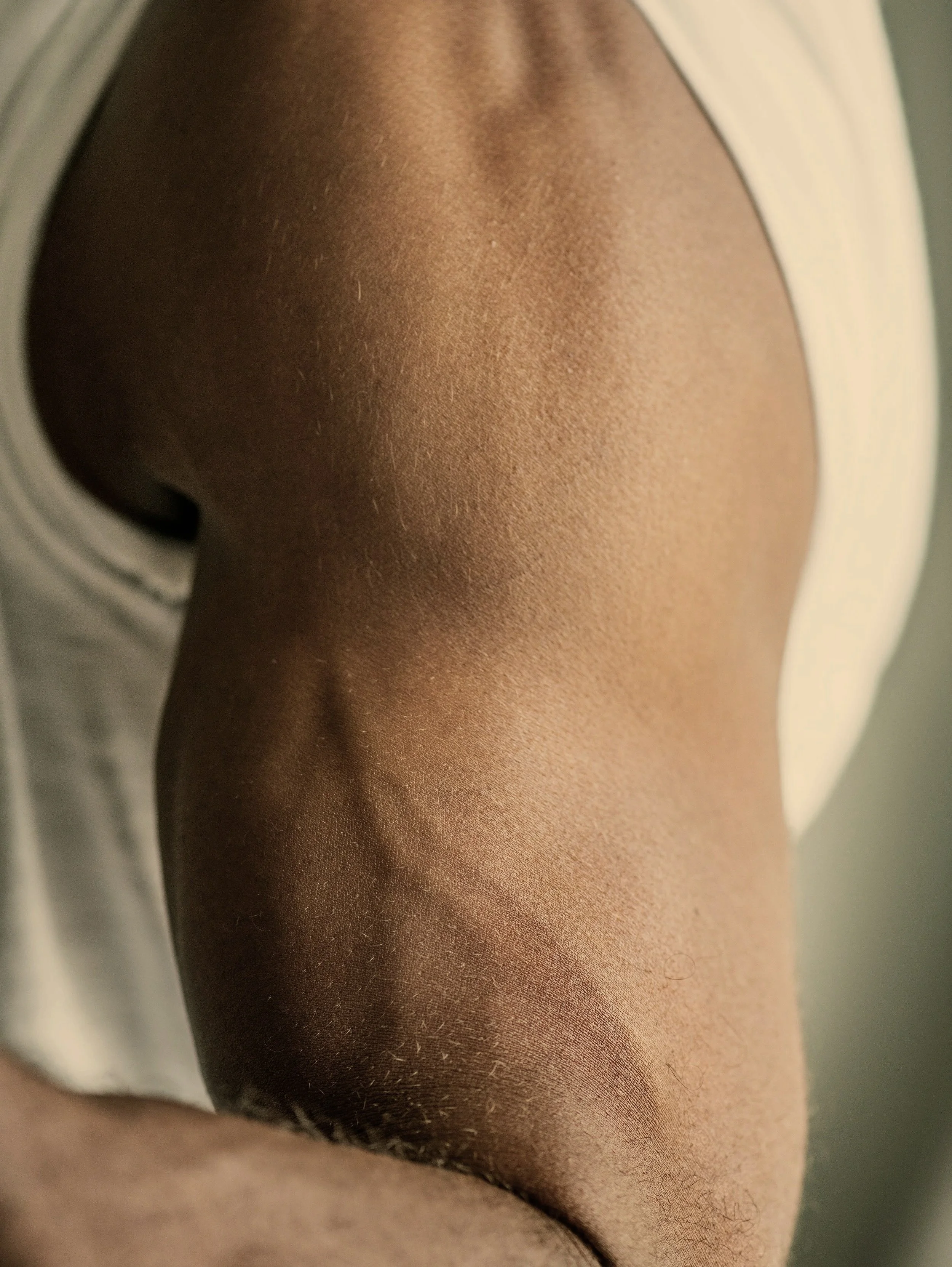 Close-up of a person's shoulder and upper arm with smooth skin, wearing a light-colored shirt.