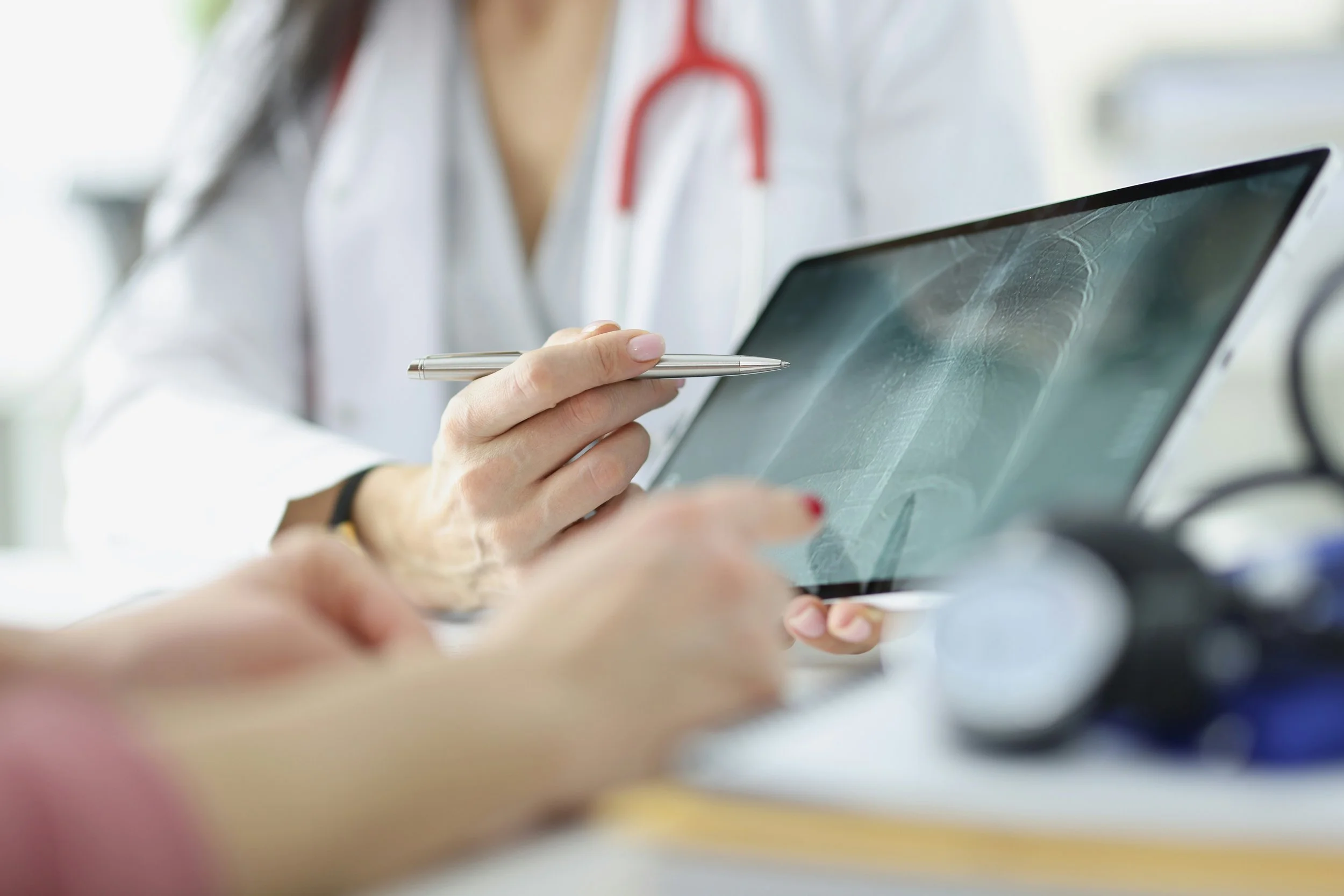 Doctor showing an X-ray image on a tablet to a patient in a medical consultation.