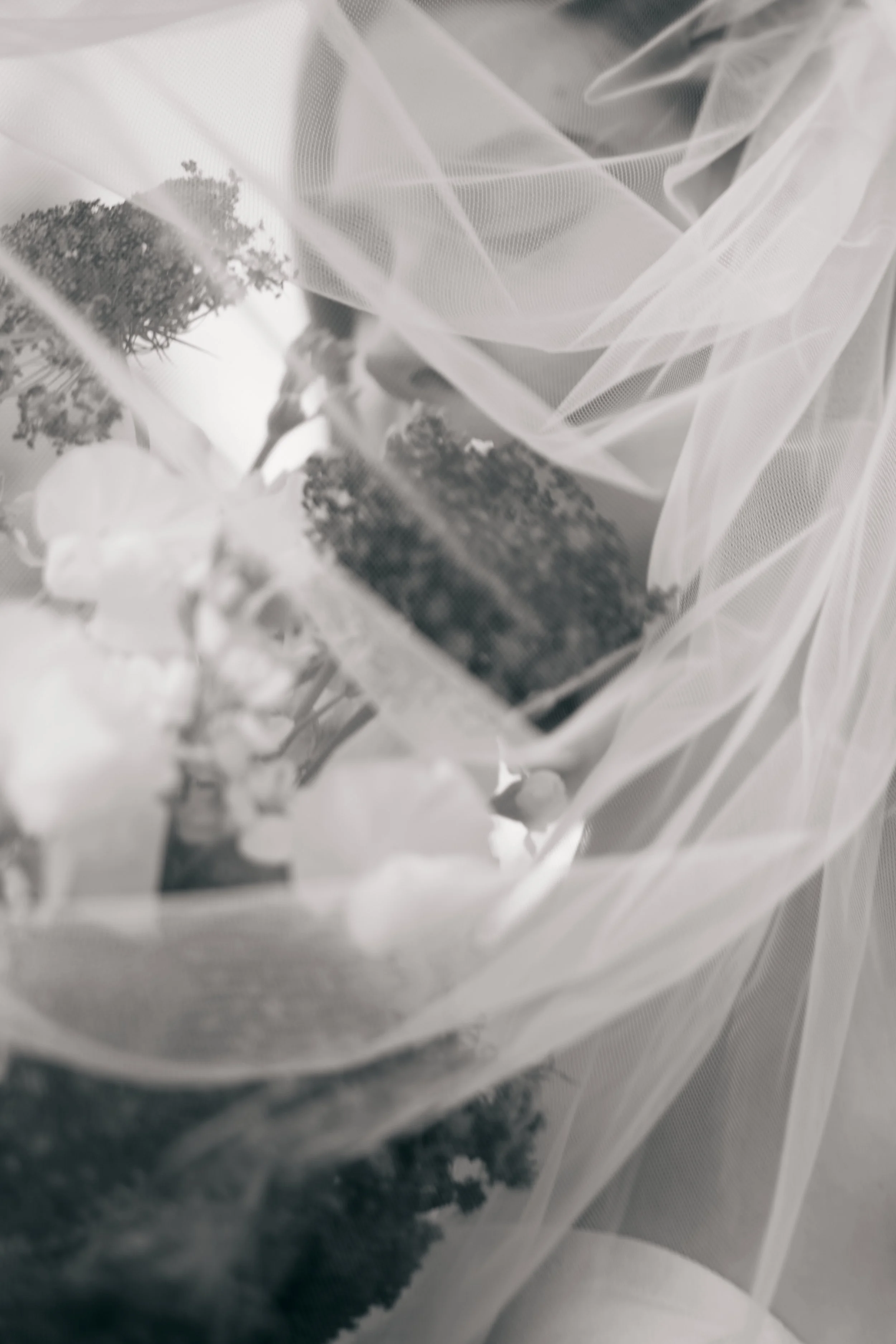 Black and white close-up photo of a wedding bouquet wrapped in sheer fabric.