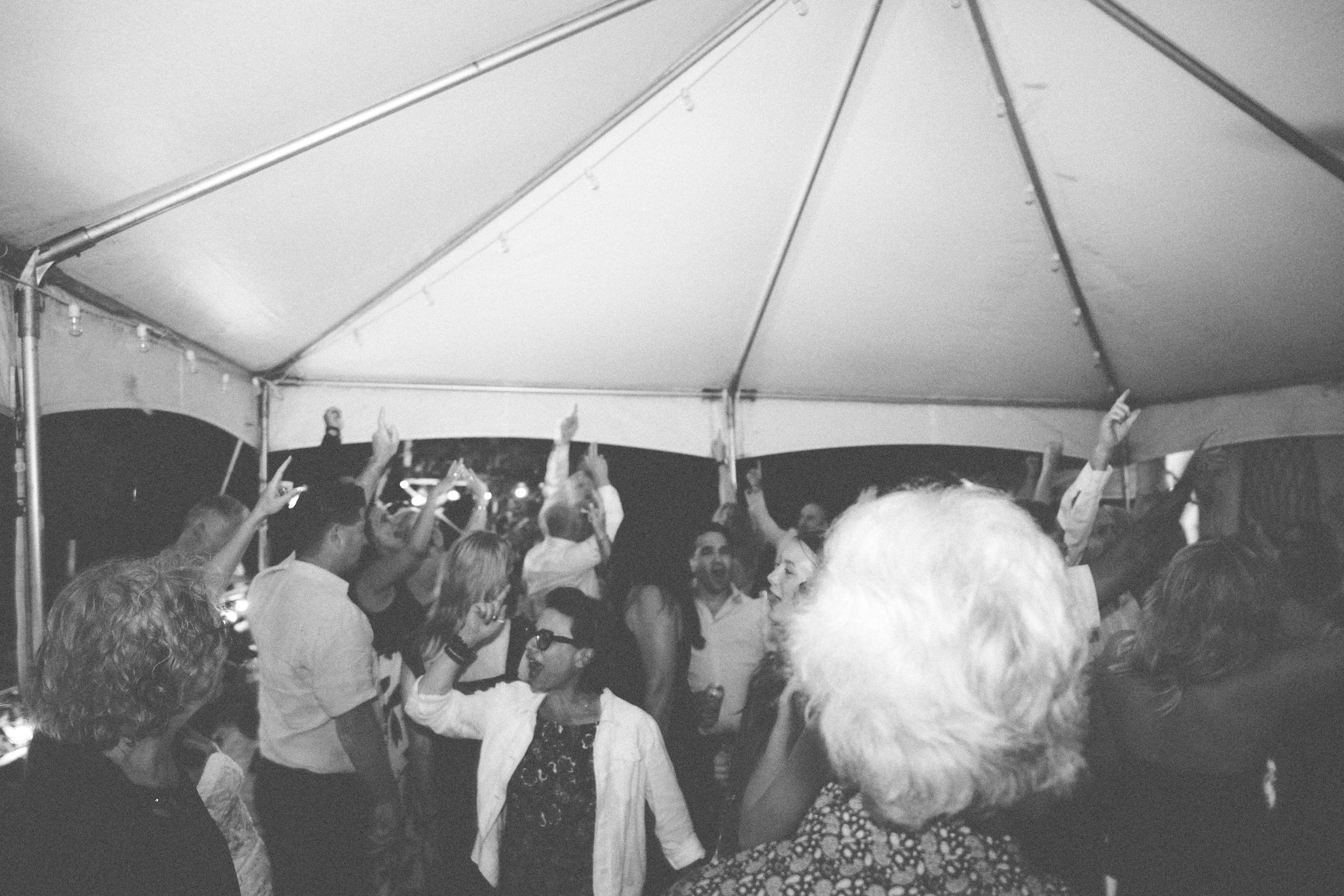 Group of people dancing and socializing under a large canopy tent at night