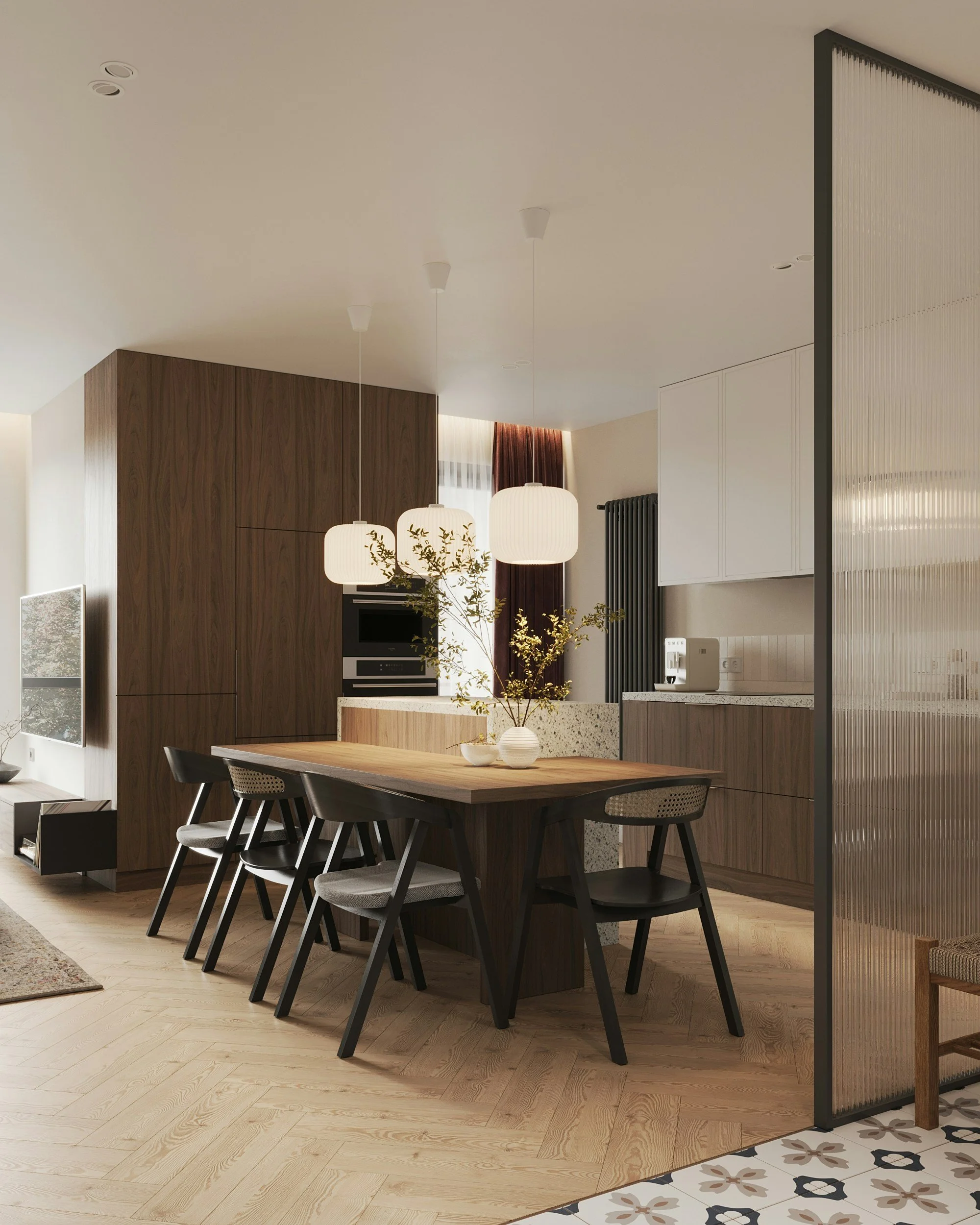 Modern dining area with a wooden table, black chairs, hanging pendant lights, and a partial view of a kitchen with white cabinets and patterned tile flooring.