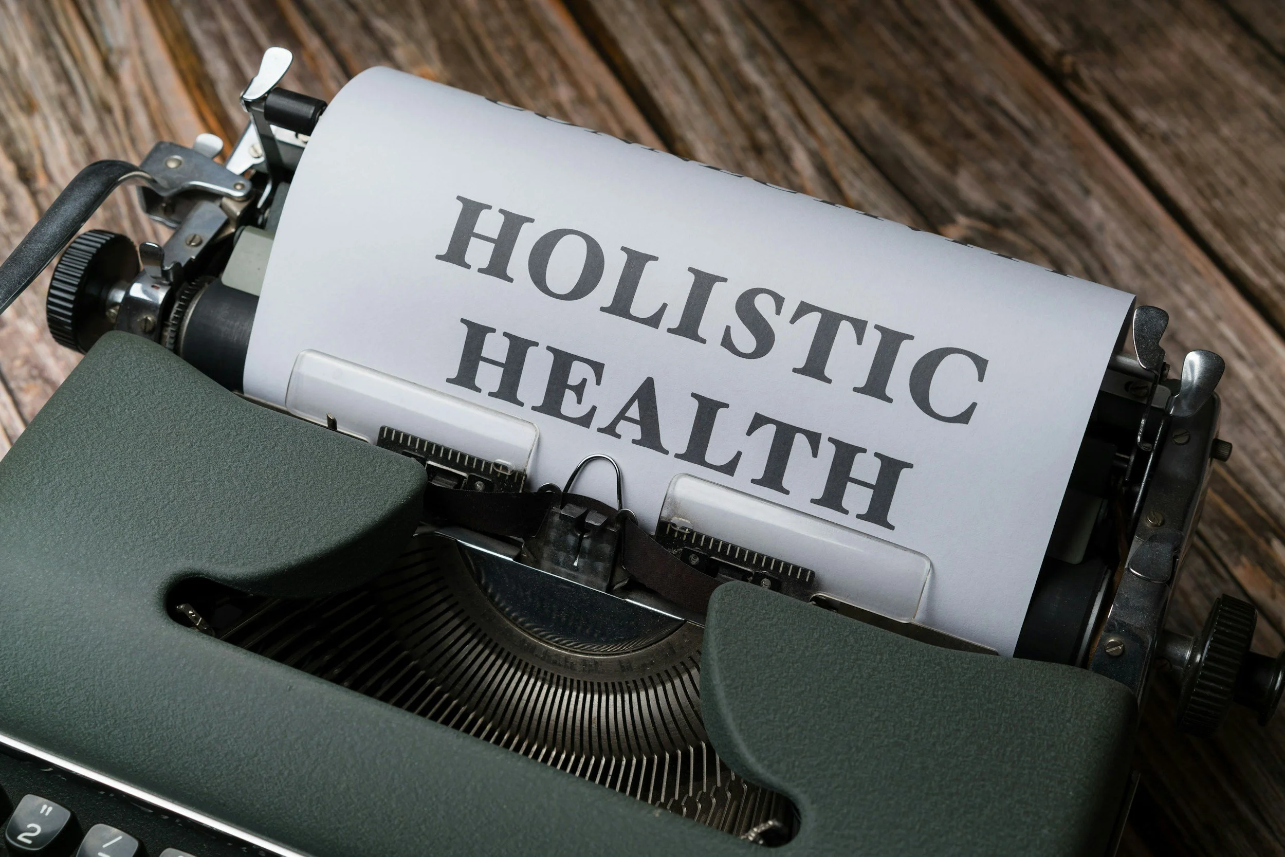 A typewriter with a sheet of paper that says 'HOLLISTIC HEALTH' on it.