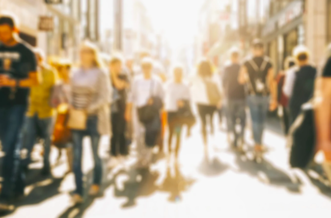 People walking on a busy city street in bright sunlight