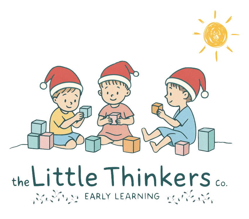 Three children wearing Santa hats sitting on the floor, playing with building blocks under a sunny sky with a bright sun in the background.