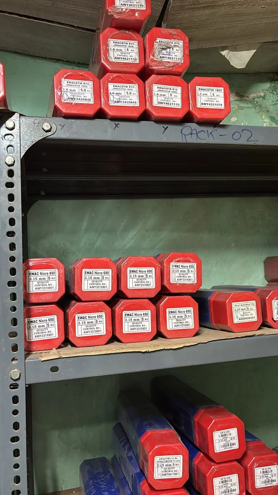 Industrial storage shelf with red and blue boxes labeled with specifications, organized on metal racks.