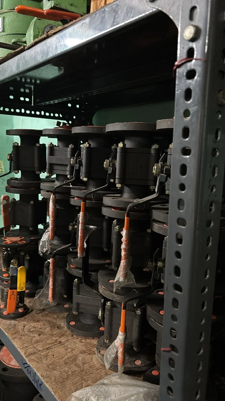 Electrical components with multiple black motors or switches mounted on a wooden shelf in a storage rack.