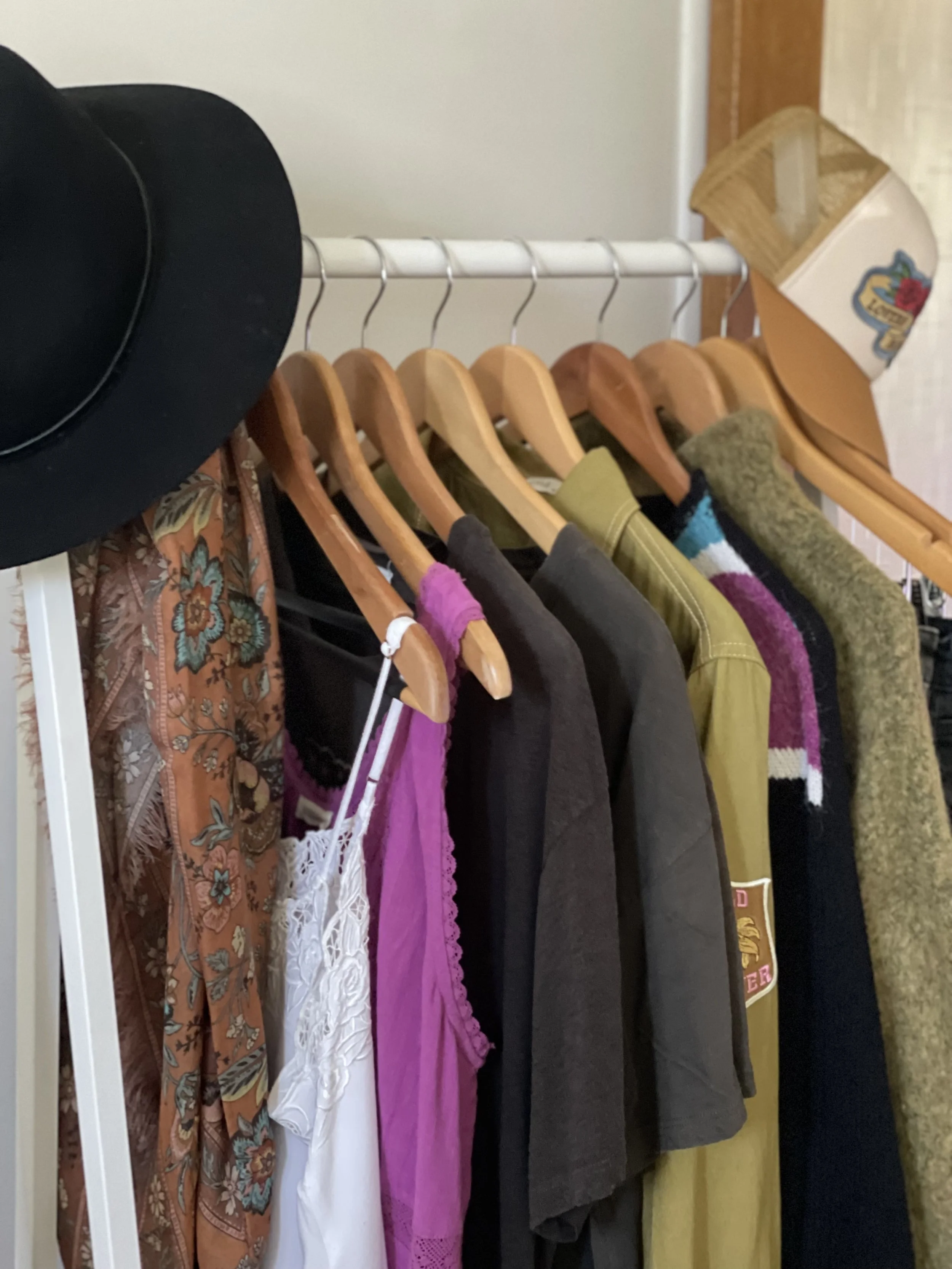 Rack of clothes neatly hanging with hats