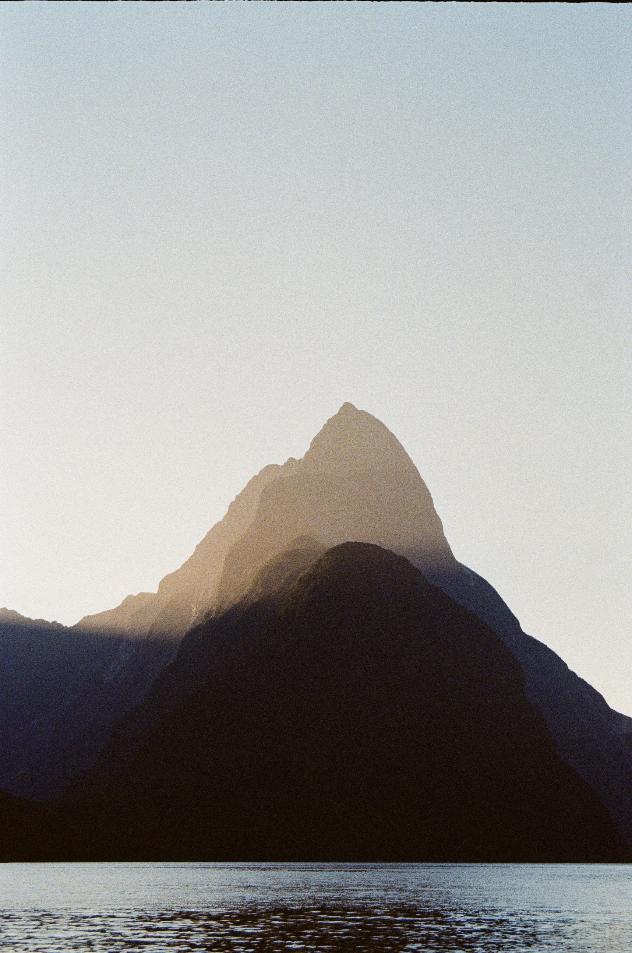 Fels im Wasser mit Sonne im Hintergrund – visuelle Metapher für tiefe Klarheit und echte Begegnung in der Zusammenarbeit.