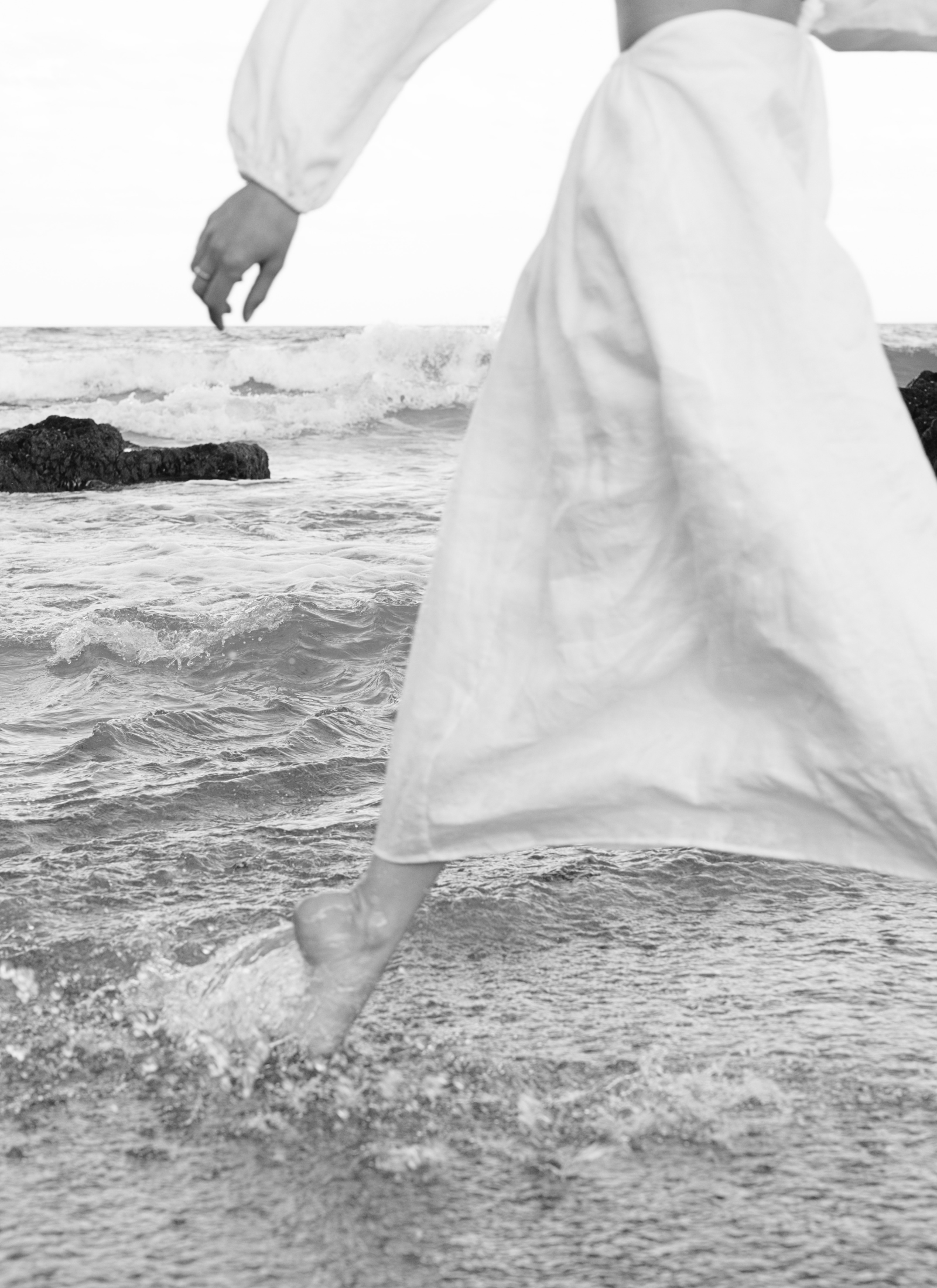 Frau läuft durch das Meer als Symbol für Verkörperung, Bewegung und Umsetzung.