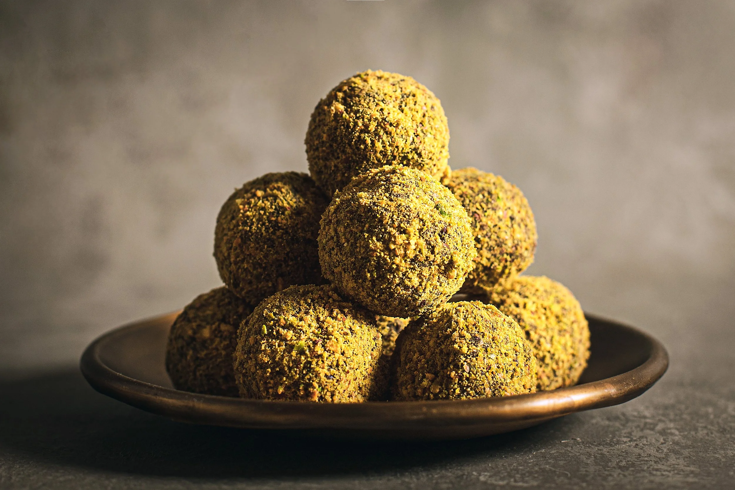Piernas de falafel apiladas en un plato de cerámica, con fondo gris.