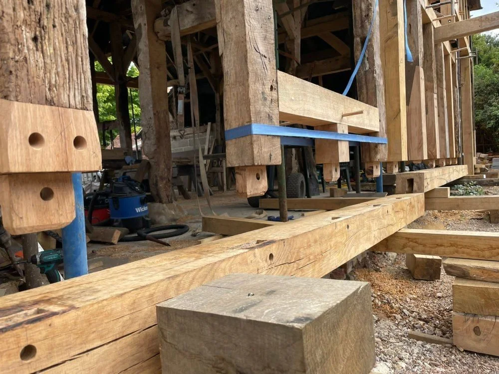 Wooden construction framing during building process with blue support straps and construction tools around.