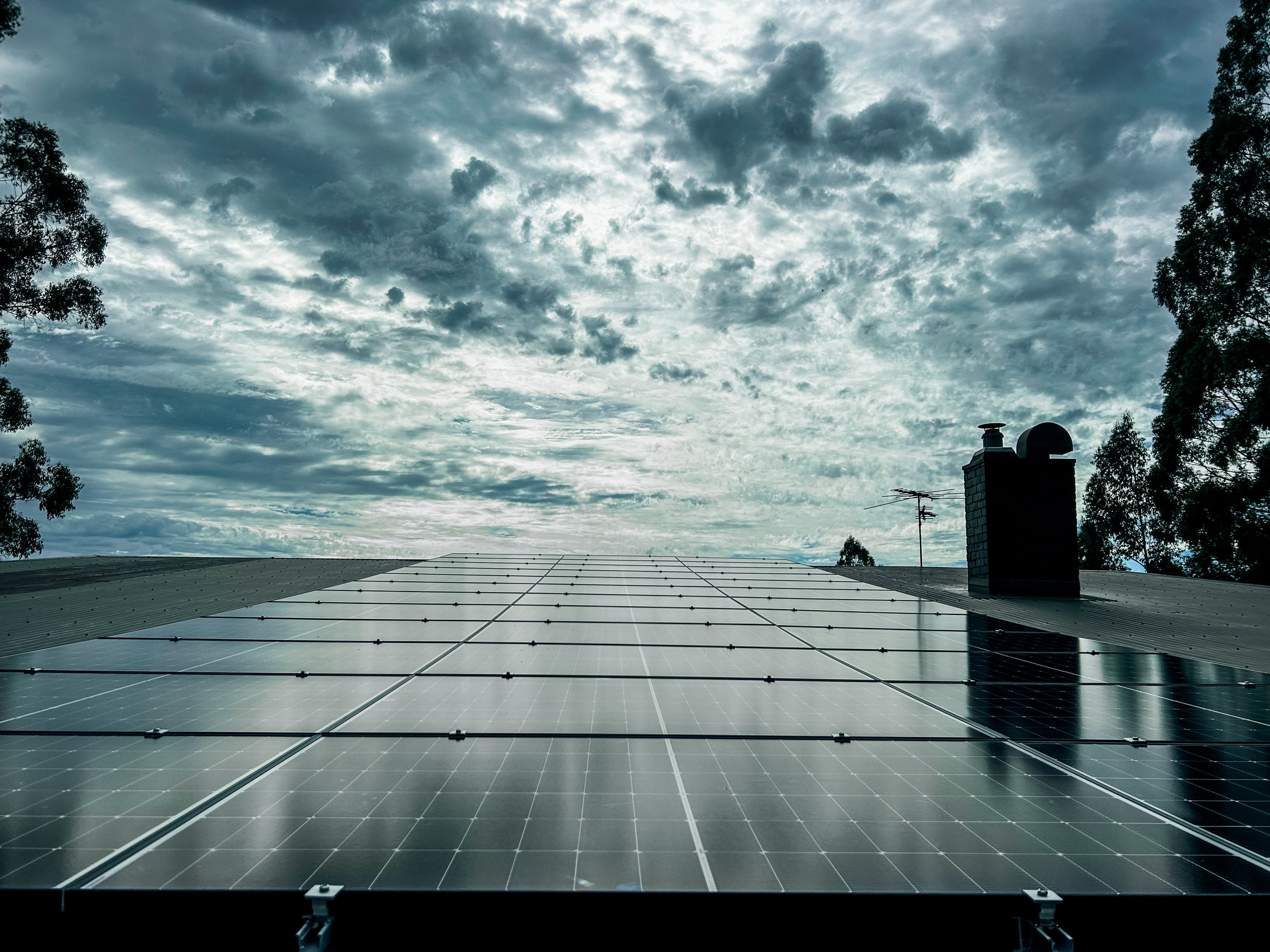 View of solar panels installed by Livesay Electrical on a roof with a cloudy sky in the background.