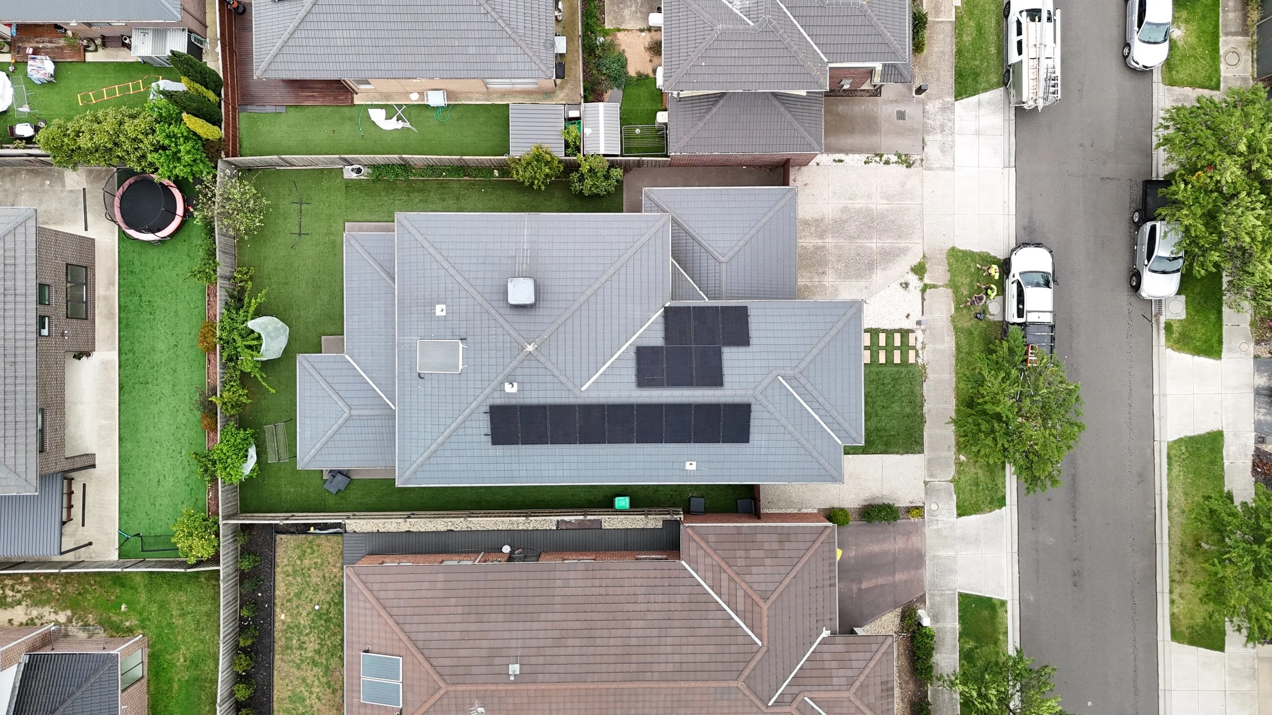 An aerial view of a house with solar panels on its gray roof