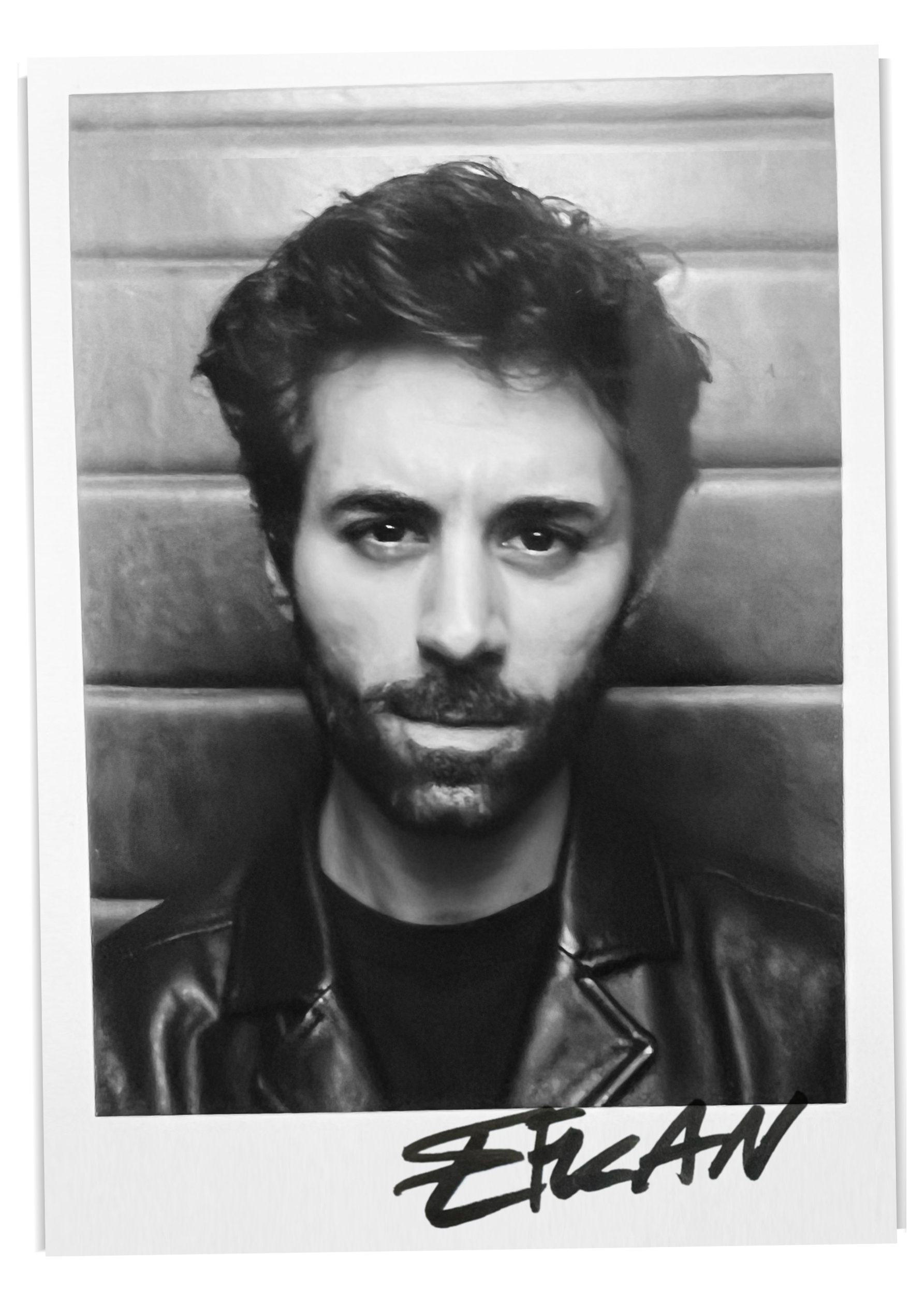 Schwarz-Weiß-Fotografie eines Mannes mit dunklem, lockigem Haar und Bart, der eine Lederjacke trägt, vor einer Holzvertäfelung. Unten ist der Name ‚EIGAN‘ geschrieben.