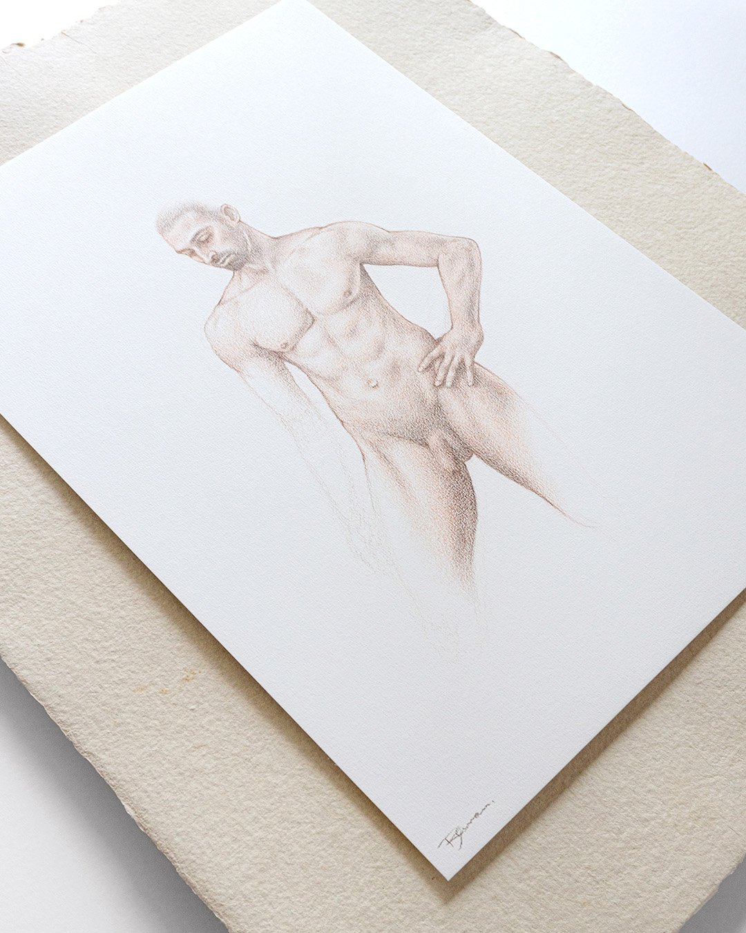 A detailed coloured pencil drawing of a nude man with a muscular physique, with his right hand resting on his hip. The artwork is on textured white paper placed on a beige surface.