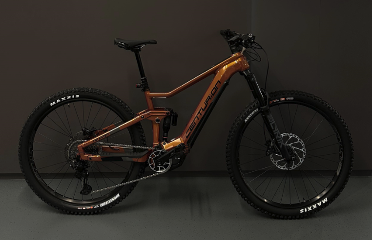 Ein modernes E-Bike mit braunem Rahmen und schwarzen Reifen, das im Innenraum steht.
