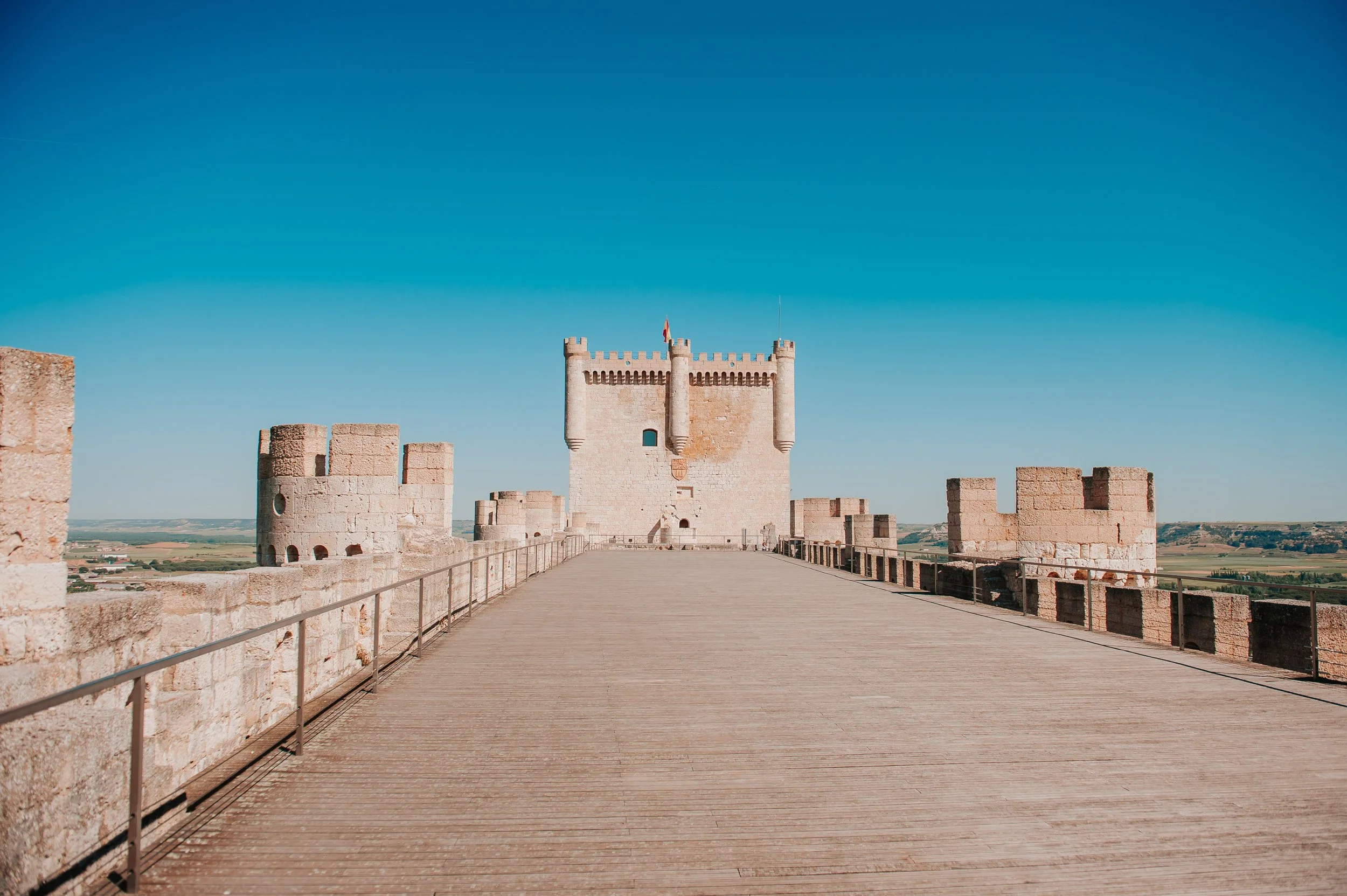Castillo medieval de piedra en un entorno rural bajo un cielo despejado.