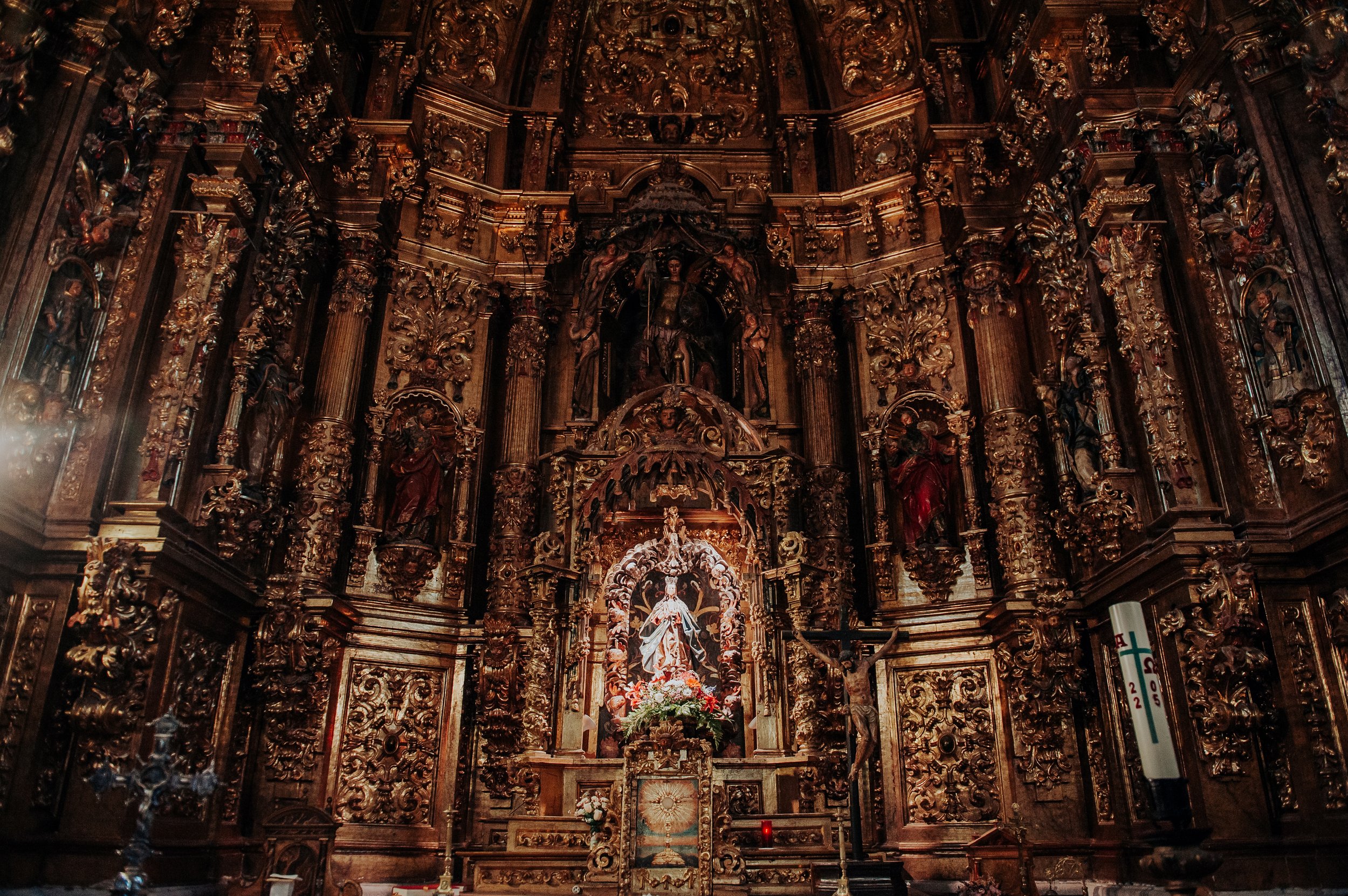 Retablo de madera dorada y detalles religiosos en un interior de iglesia.