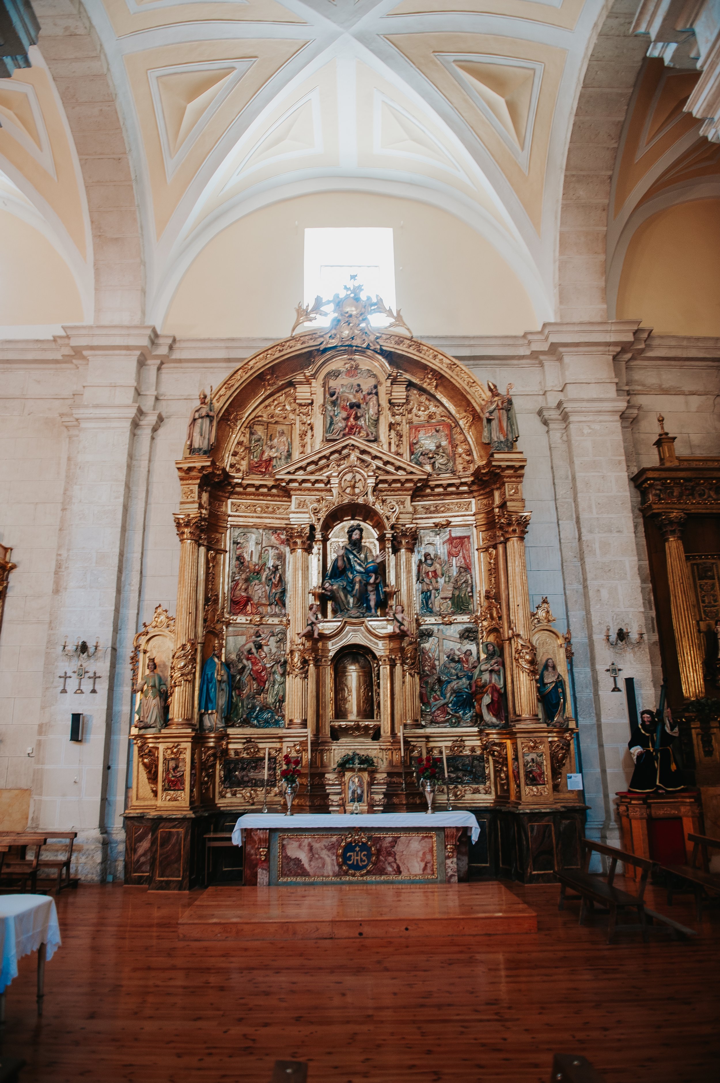 Retablo dorado en interiores de iglesia, con esculturas religiosas y altar de madera.