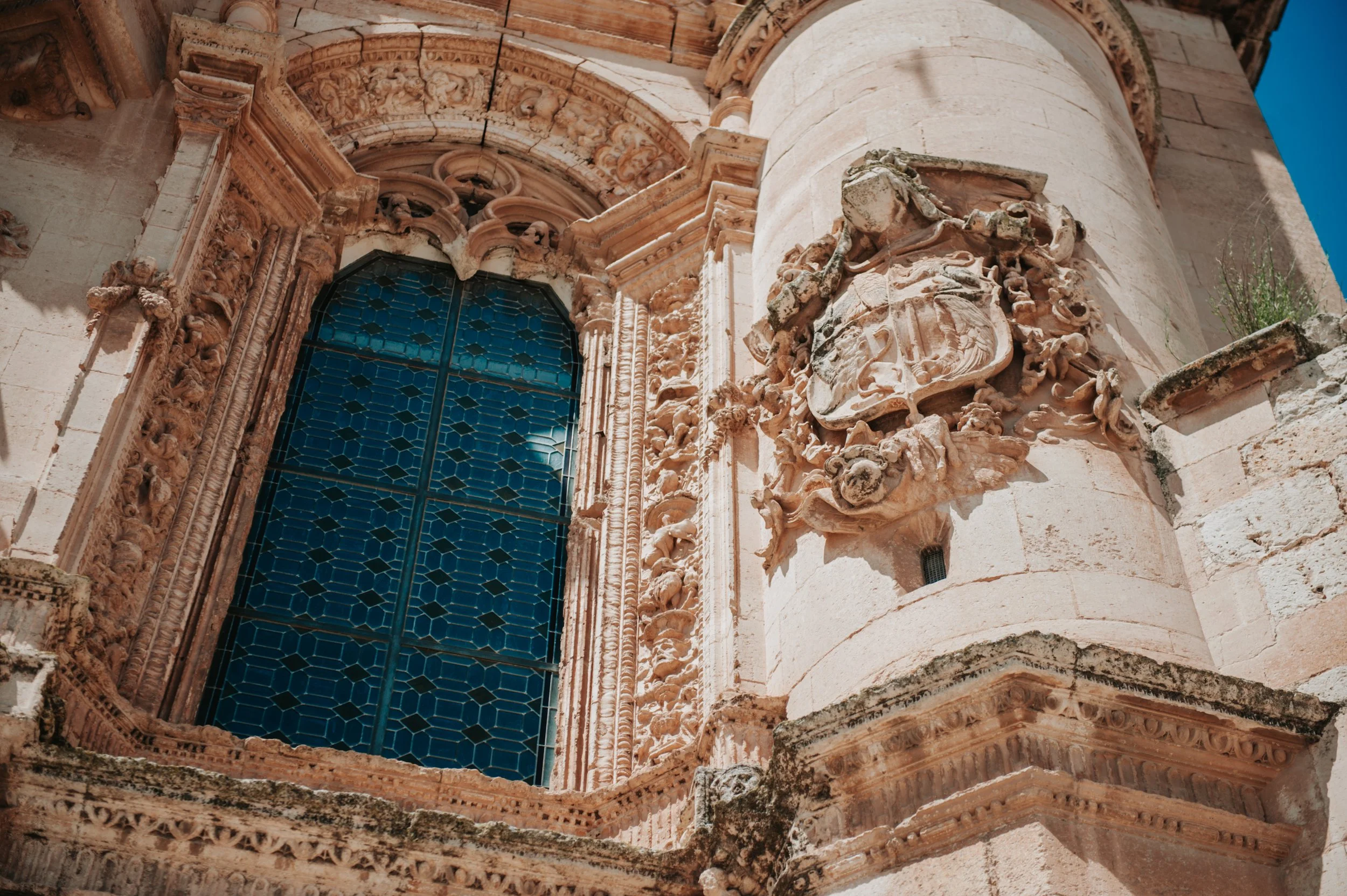 Detalle de la fachada de una iglesia antigua con una ventana de vidrio de colores y decoraciones escultóricas en piedra