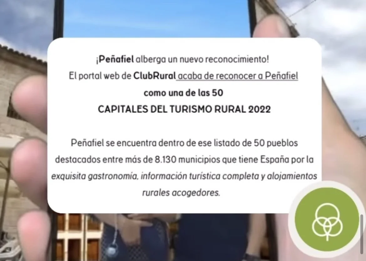 Notificación en una pantalla de teléfono que informa que Peñafiel es una de las 50 capitales del turismo rural en 2022, destacando su gastronomía y alojamientos rurales en España.