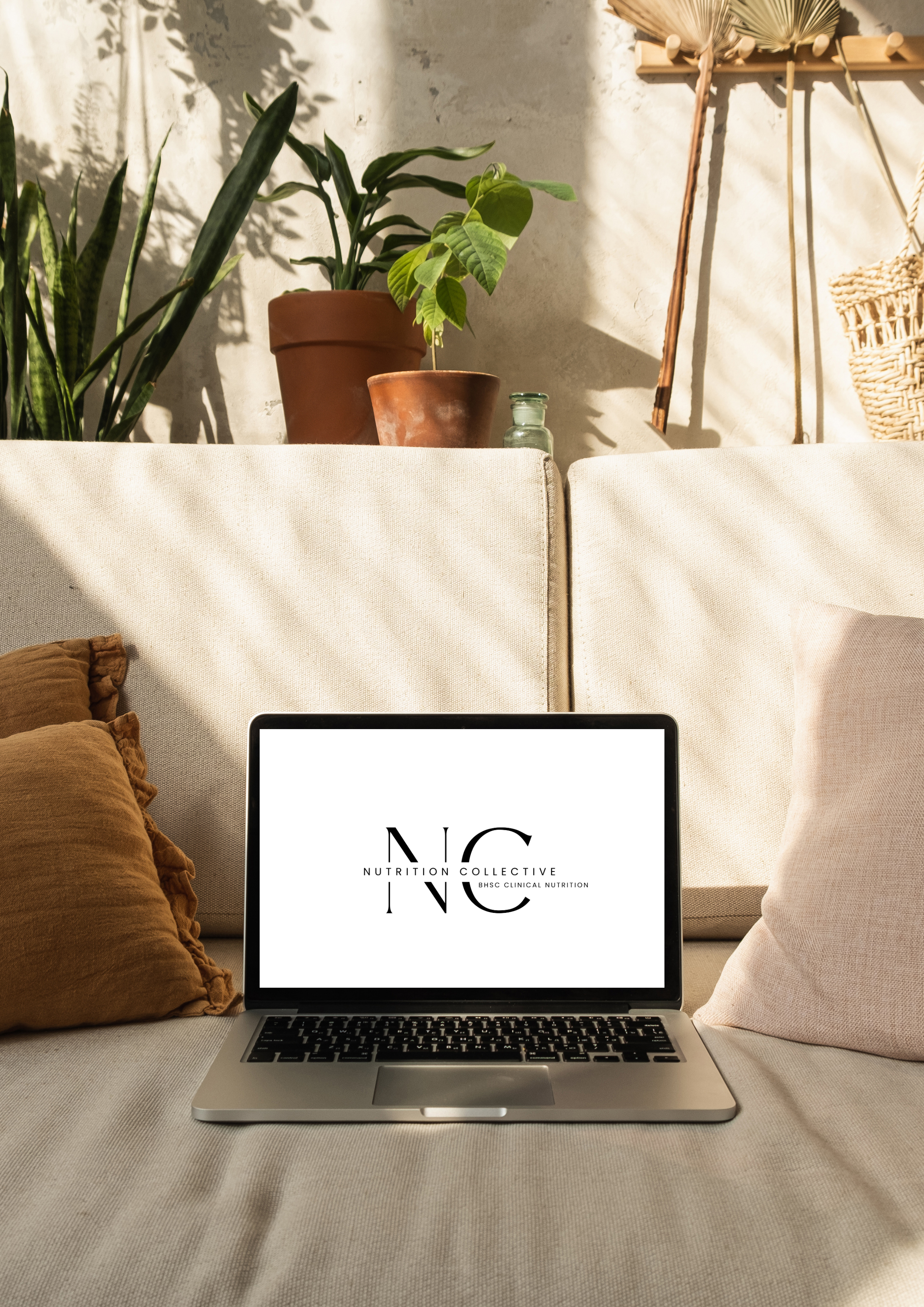 A laptop on a beige sofa displaying the Nutrition Collective logo with a plant and wall decor in the background. Nutrition Collective. Clinic Space. Clinic Work. Dedication. Modern. Advanced. Expert. Nutrition Collective - DNA nutrigenomics. MTHFR.