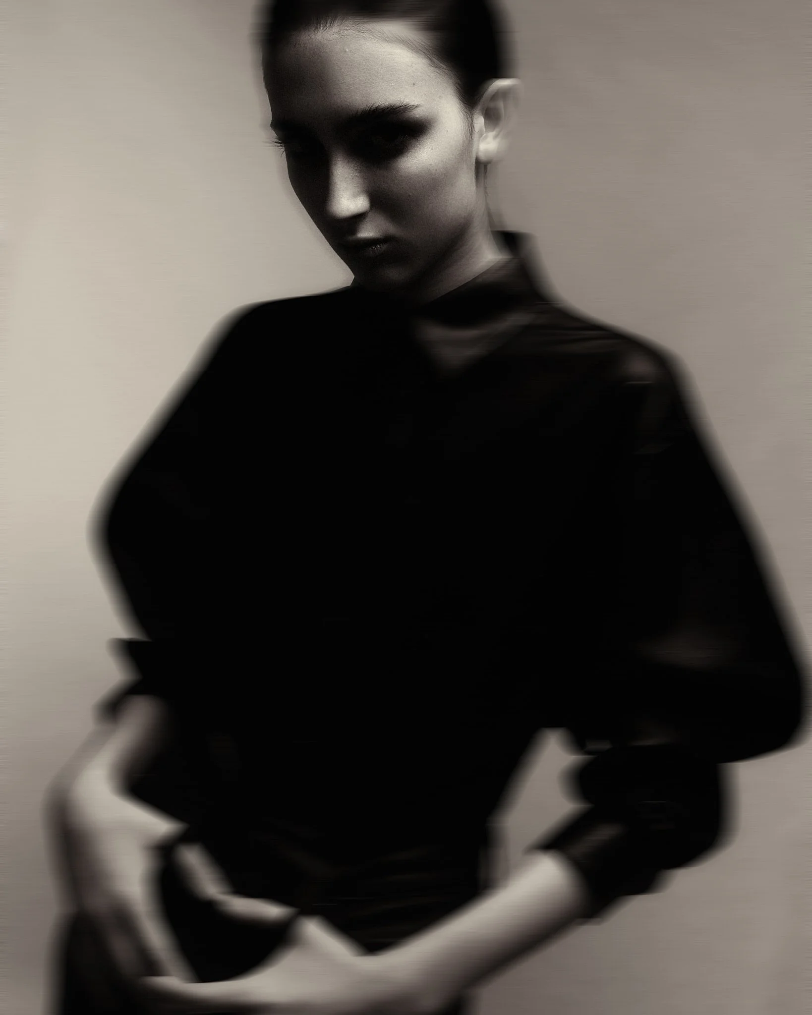 Black and white portrait of a woman with intense expression, blurred background, wearing dark clothing.